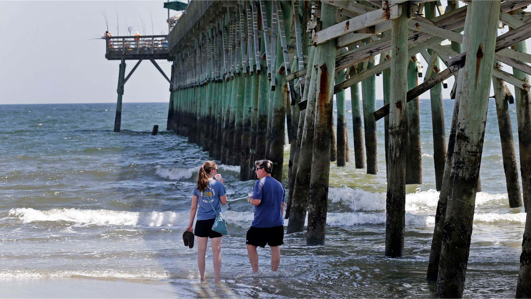 June 15, 2015: Doug Baucom, right, of Wadesboro, talks with his daughter Katie Reynolds, left, of Boone, N.C., as they stand in the surf by the Ocean Crest Pier in Oak Island, N.C.,
