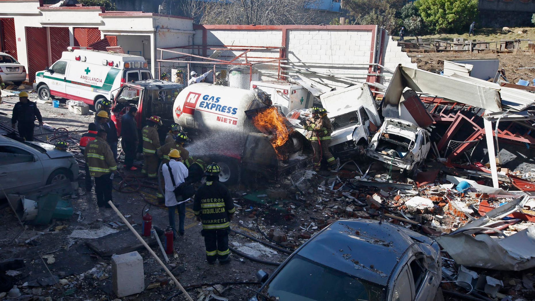 FILE - In this Jan. 29, 2015 file photo, firefighters spray water on a gas truck that caused an explosion and killed five at a maternity and children's hospital in Cuajimalpa on the outskirts of Mexico City. Mexican officials said Monday, Feb. 16, 2015 that two worn-out bolts on the gas tanker truck caused a leak that resulted in the explosion. Experts said wire and Teflon tape had been improperly used on parts of the truck's valves, and Mexico City chief prosecutor Rodolfo Rios said one of the bolts was the wrong size, and the truck's gas meter had been altered to shortchange customers. (AP Photo, File)