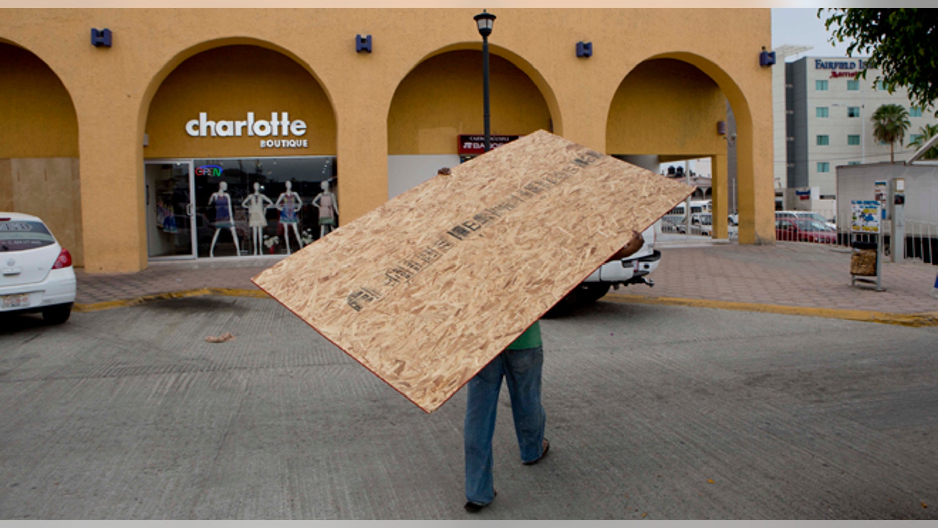 A worker hauls a board to use on a storefront window as protection against Hurricane Blanca in Cabo San Lucas, Mexico, Saturday June 6, 2015. The unpredictable Blanca, which strengthened suddenly from a Category 1 to a Category 4 storm on Saturday before weakening slightly, is expected to make landfall as a tropical storm on Monday. But authorities said its outer bands could start hitting the southern Baja California Peninsula as a hurricane on Sunday. (AP Photo/Eduardo Verdugo)