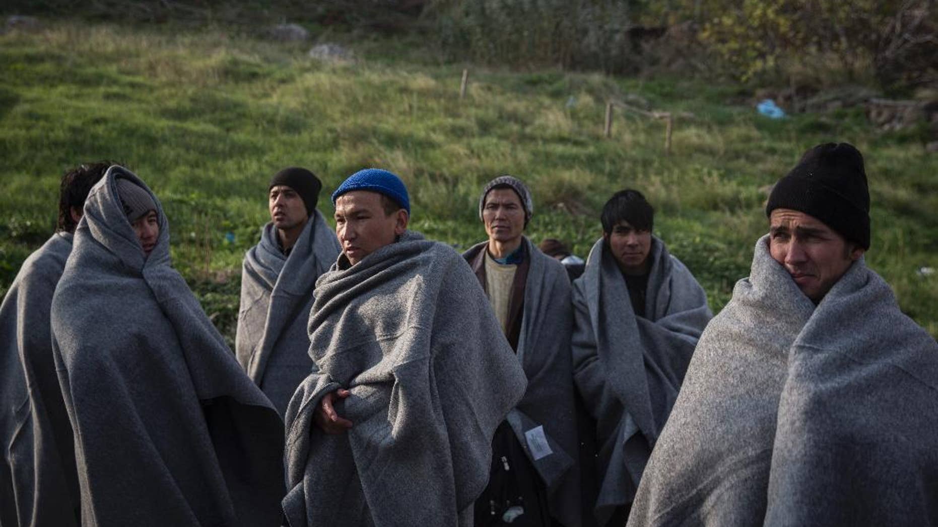 Migrants and refugees try to keep themselves warm with blankets, after the boat on which they crossed a part of the Aegean sea from Turkey hit on rocks, on the Greek island of Lesbos, on Saturday, Dec. 12, 2015. Any link between extremism and the thousands of people fleeing violence in Syria and elsewhere is false, a top European human rights official said Friday, noting that those who have perpetrated recent attacks in Europe were citizens of European countries.(AP Photo/Santi Palacios)