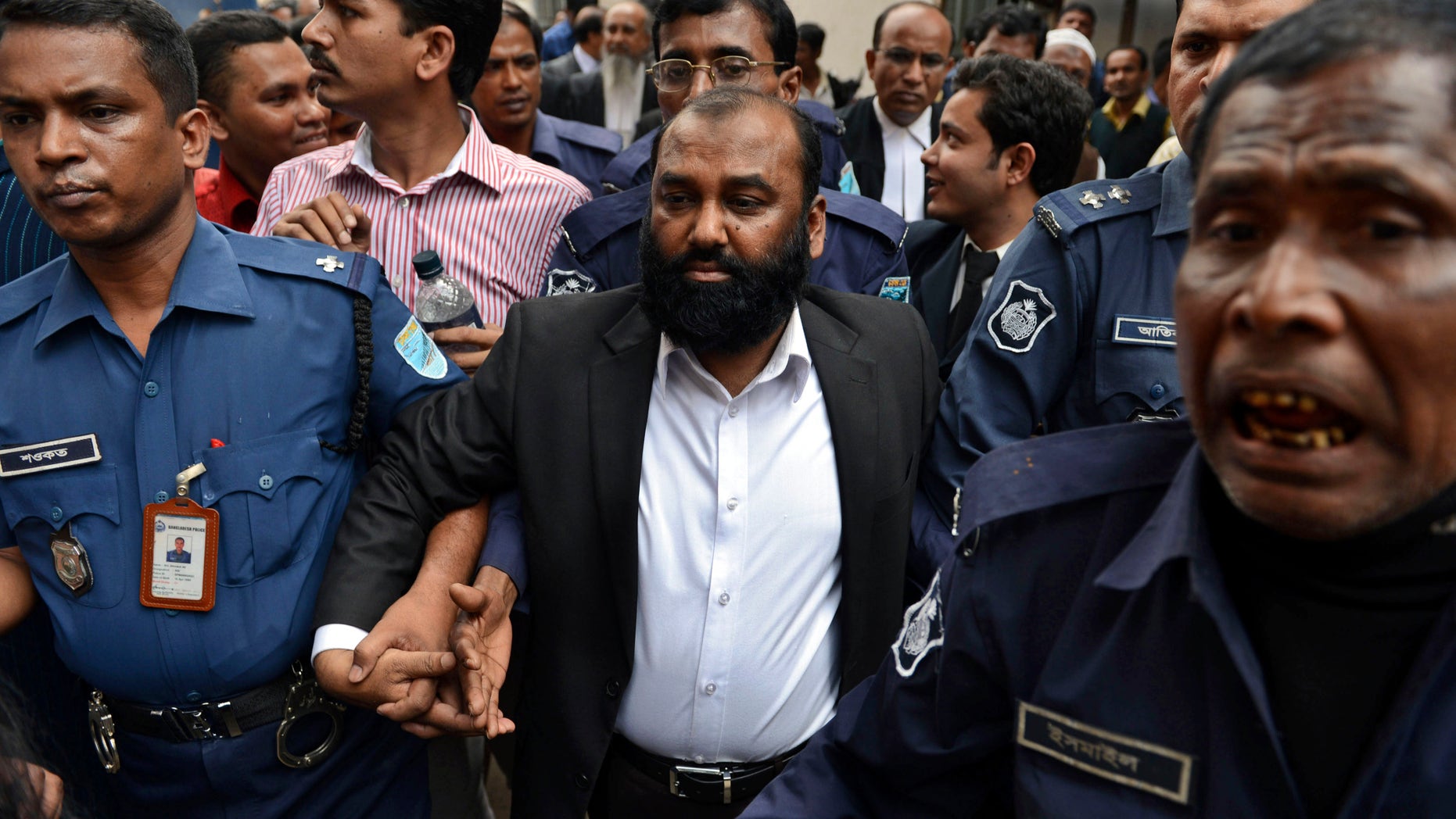 One of the two owners of Tazreen Fashions Ltd., Delwar Hossain, center, is escorted by security personnel to a court in Dhaka, Bangladesh, Sunday, Feb. 9, 2014. Two owners of a Bangladesh garment factory where 112 workers died in a fire two years ago surrendered on Sunday and sought bail after they were charged with homicide. (AP Photo)