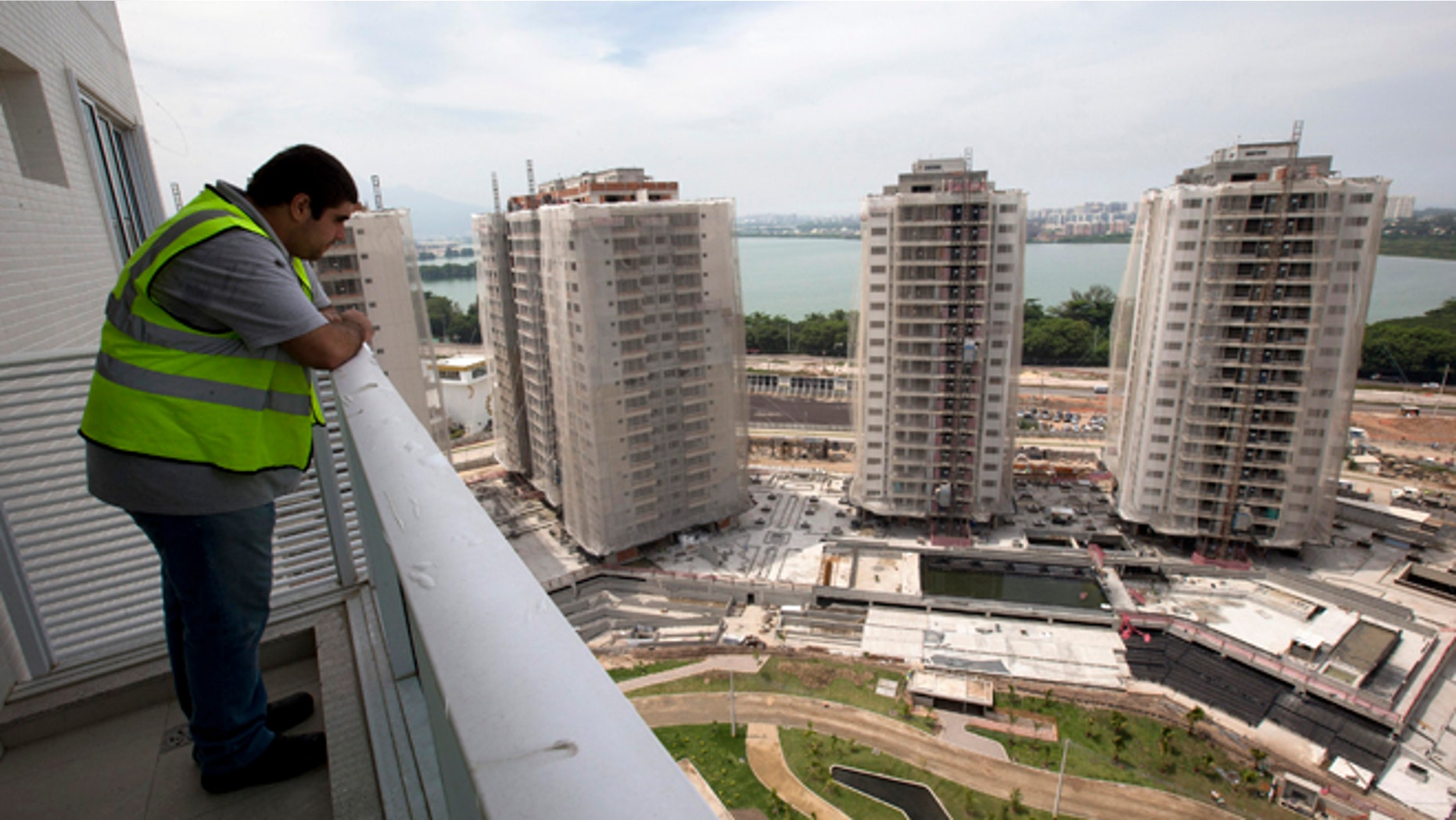 In this March 16, 2015 photo, a worker stands on the balcony of an apartment inside the Rio 2016 Olympic Games athletes village in Rio de Janeiro, Brazil. Christopher Gaffney, who spent 5 1/2 years in Rio researching the 2014 World Cup and Olympics, called the village "a transfer of wealth program from the public (treasury) to private construction firms." (AP Photo/Silvia Izquierdo)