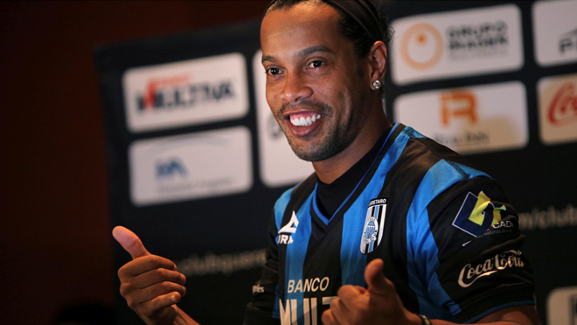 FILE - In this Sept. 12, 2014 file photo, Brazil's Ronaldinho poses for a photo after slipping on his new Queretaro soccer club jersey at a press conference in Mexico City. Mexican first-division club Queretaro signed the former 34-year-old soccer star, who had been without a club since leaving Brazil's Atletico Mineiro in July and had been negotiating with several clubs. The upbeat mood of his signing didn't last long. Even before he had played his first match, Ronaldinho became the subject of a racist attack _ the kind that have become common with black football players across Europe. (AP Photo/Marco Ugarte)