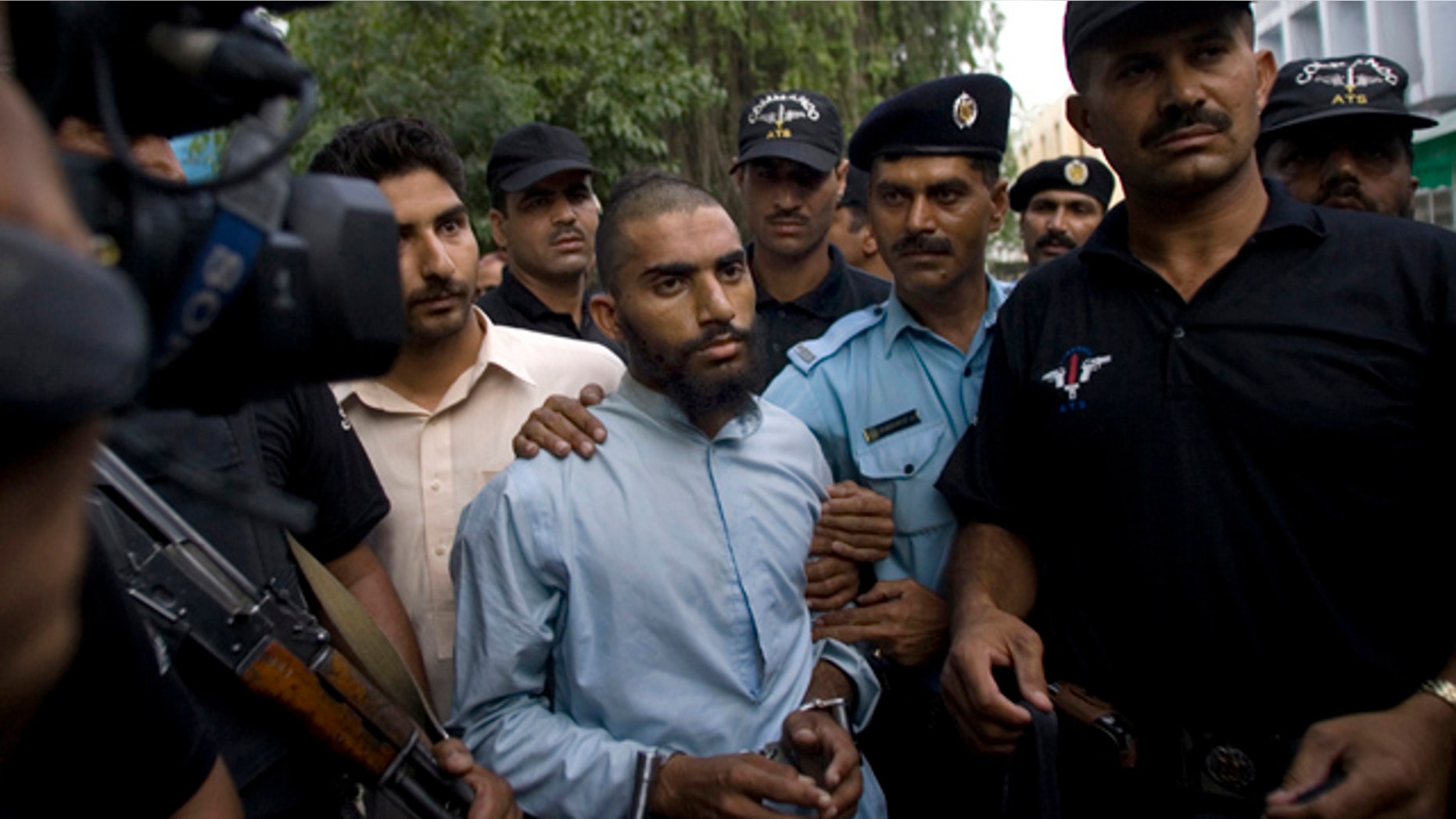 FILE - In this June 1, 2009 file photo, Pakistani police officers escort detained suspect militant Fida Ullah, center, who studied from radical Red Mosque in Islamabad, Pakistan. Pakistani authorities now believe a dangerous new militant group, out to avenge a deadly army assault on the mosque three years ago, has carried out several major bombings in the capital previously blamed on the Taliban. (AP Photo/Anjum Naveed, File)