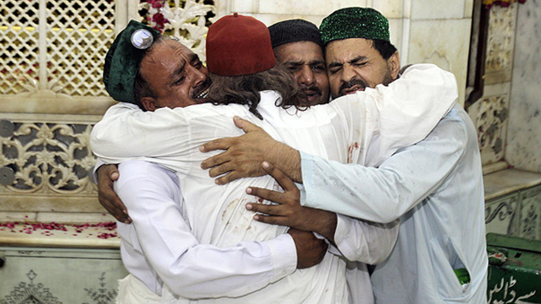 July 1: Family members of victims comfort one another after bombers attacked a popular Muslim shrine in Lahore, Pakistan.