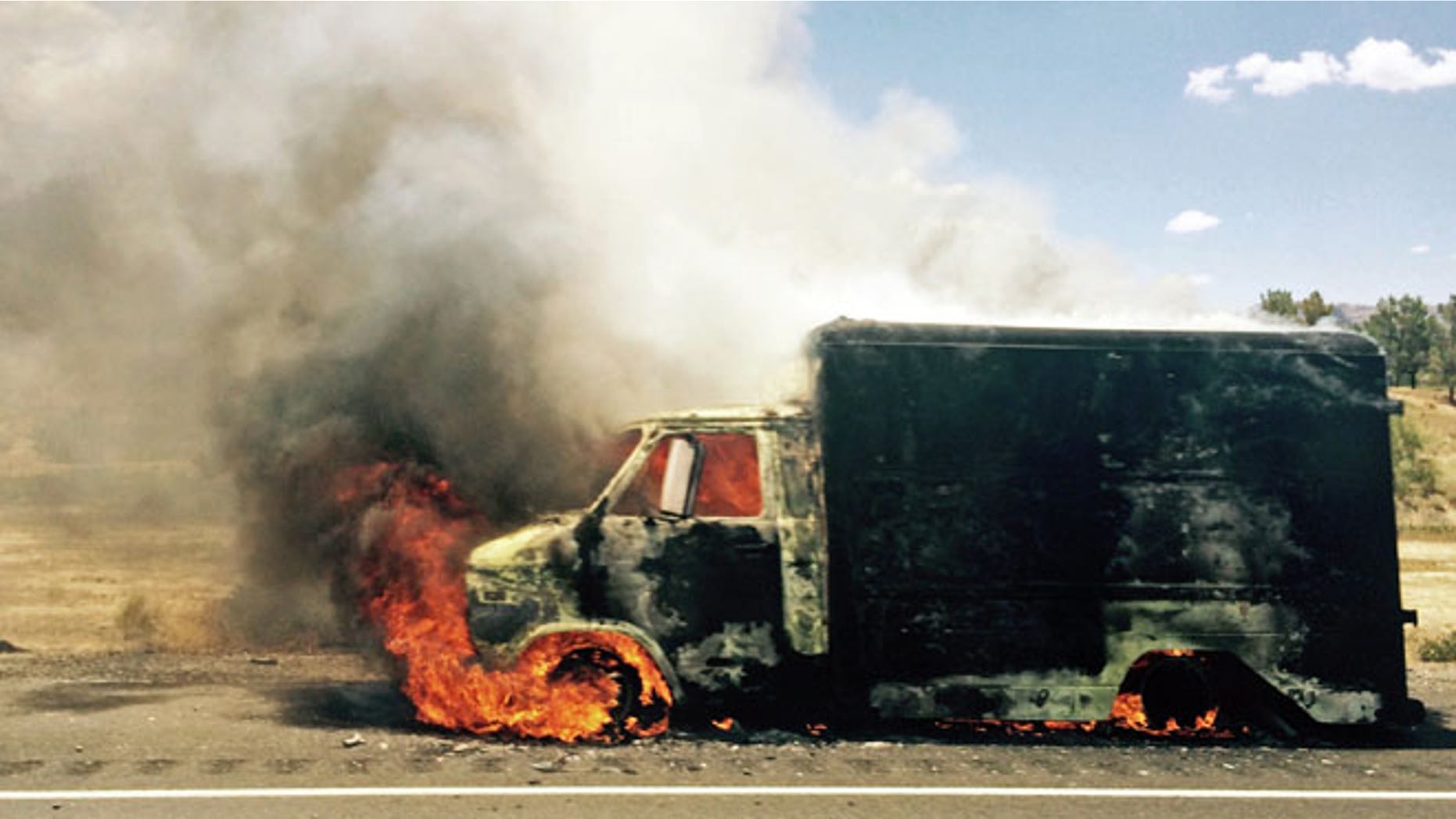 Kuly 2, 2015: In this photo provided by Jay Rutherford, smoke rises from a burning truck packed with fireworks after it exploded on Interstate 15 near Ivanpah, Calif., close to the Nevada state line.