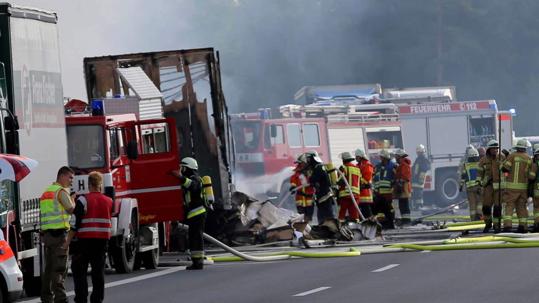 Rescue workers stand beside burnt-out coach on the motorway A9 near Muenchberg, southeastern Germany, Monday, July 3, 2017 after a bus crashed into a truck and caught fire.