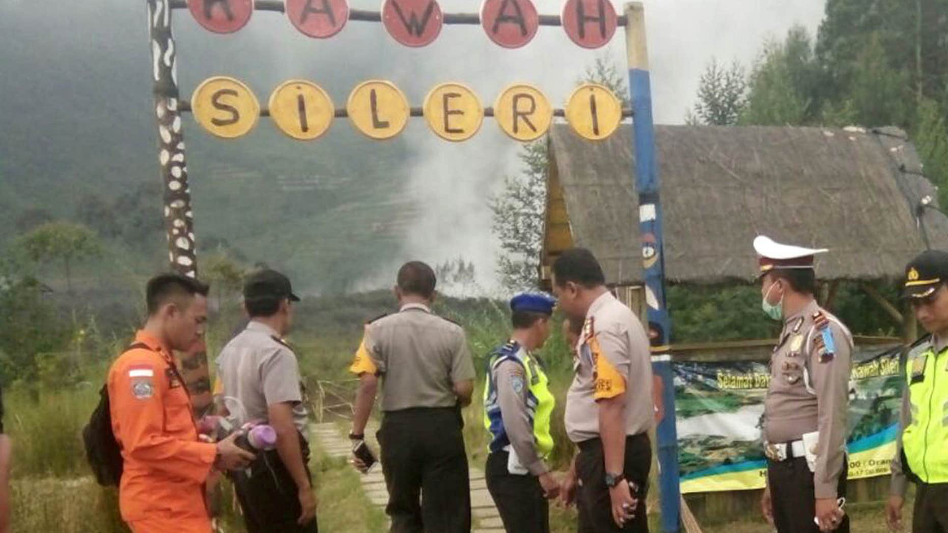 July 2, 2017: Police officers and a rescuer stand at a path leading to Sileri Crater after it erupted in Dieng, Central Java, Indonesia.