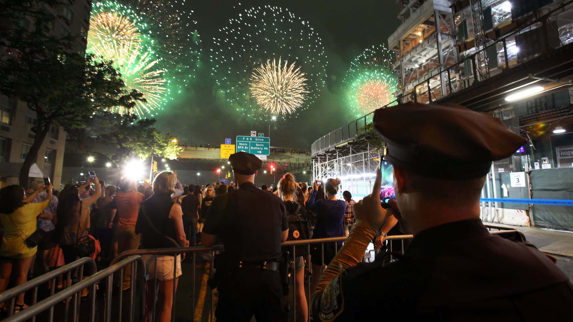 A New York City police officer takes a picture with his phone as he watches over spectators watching the Fourth of July fireworks, Monday, July 4, 2016, along the East River on the FDR Drive in New York.