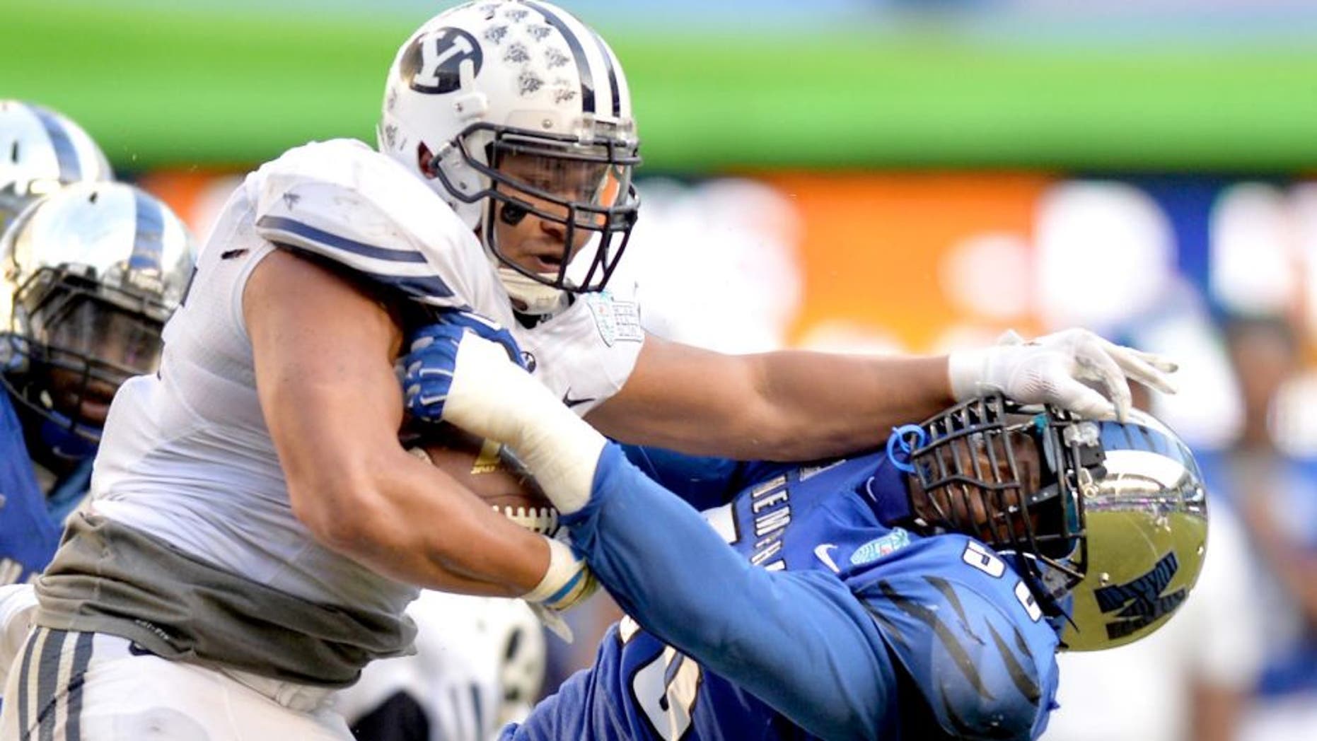 Dec 22, 2014; Miami, FL, USA; Brigham Young Cougars running back Algernon Brown (24) stiff arms Memphis Tigers defensive lineman Terry Redden (56) during the third quarter in the Miami Beach Bowl at Marlins Park. Memphis won 55-48 in a double overtime. Mandatory Credit: Steve Mitchell-USA TODAY Sports