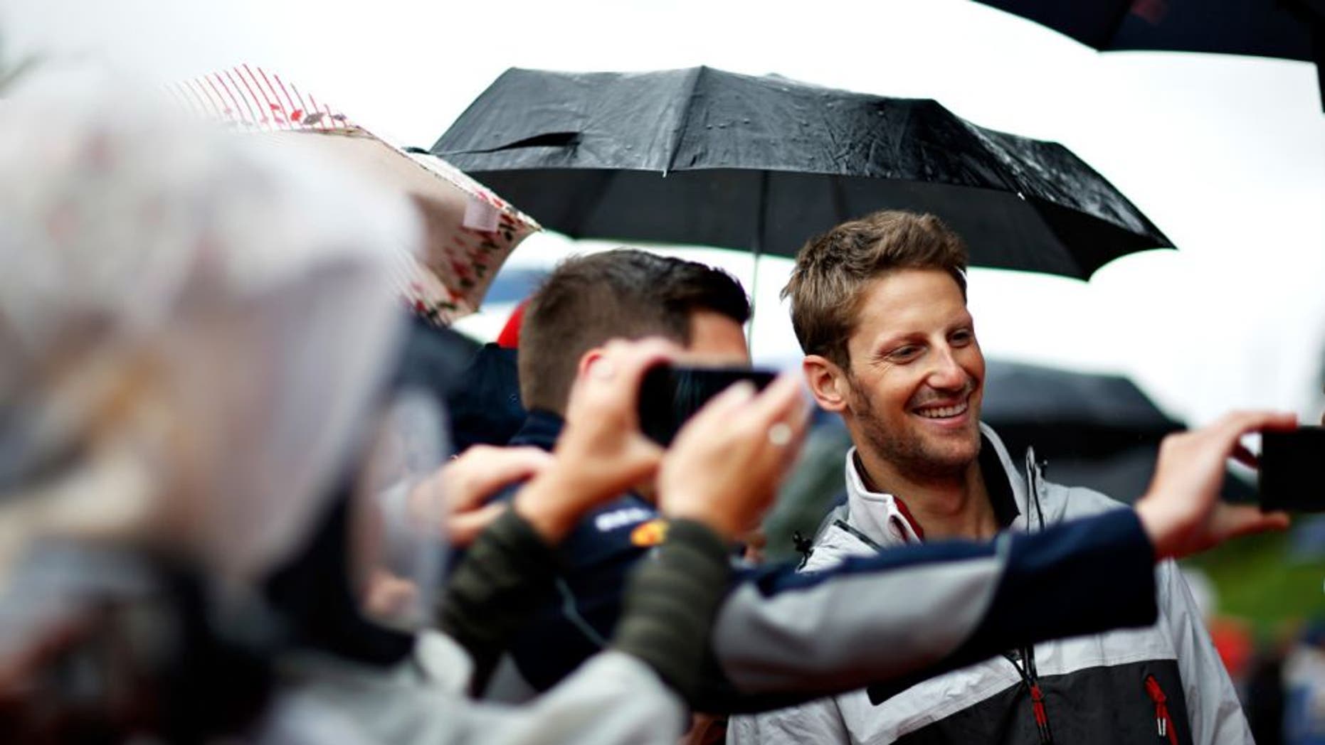 SPIELBERG, AUSTRIA - JULY 03: Romain Grosjean of France and Haas F1 poses for a photo with a fan before the Formula One Grand Prix of Austria at Red Bull Ring on July 3, 2016 in Spielberg, Austria. (Photo by Charles Coates/Getty Images)