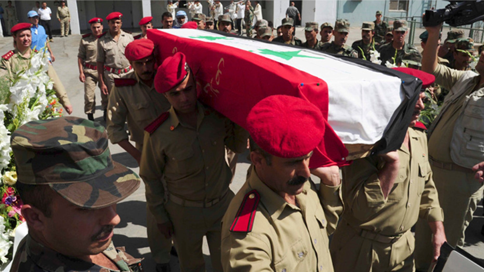 July 6: In this photo released by the Syrian official news agency SANA, Syrian soldiers carry the coffin of a comrade who was killed in recent violence in the country during his funeral procession at a hospital in Damascus, Syria.