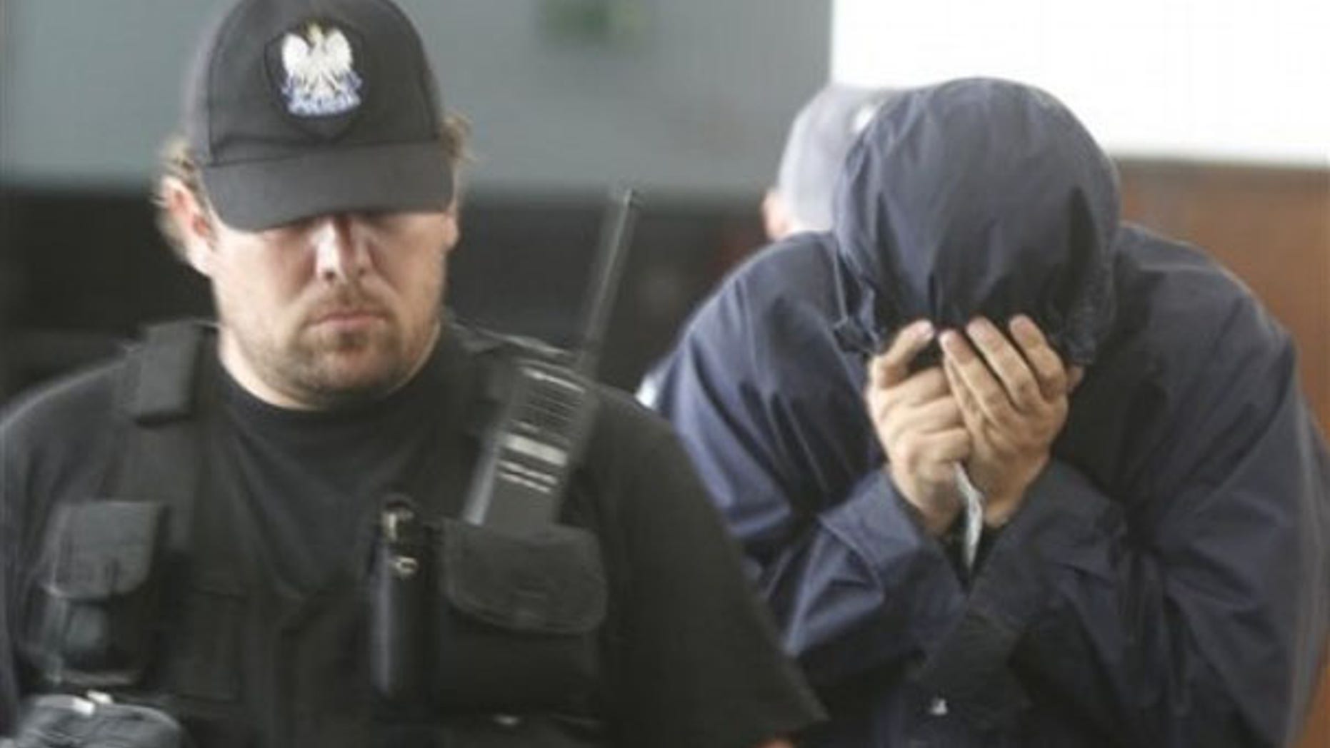 July 5: Hiding his face, Israeli citizen Uri Brodsky is escorted by police officials to a court session in Warsaw.