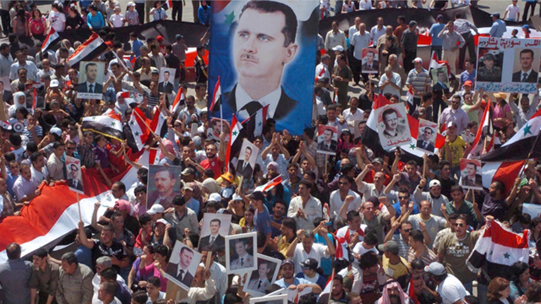 July 6: In this photo released by the Syrian official news agency SANA, pro-Syrian President Bashar Assad demonstrators display posters with his image during a gathering to show their support at Ezraa village in Daraa province, Syria.