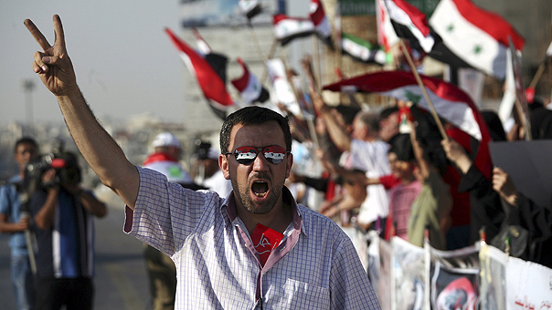 July 7: A man wearing sunglasses painted with the colors of the Syrian national flag gives a v-sign during a rally in support of the Syrian opposition in Amman, Jordan.