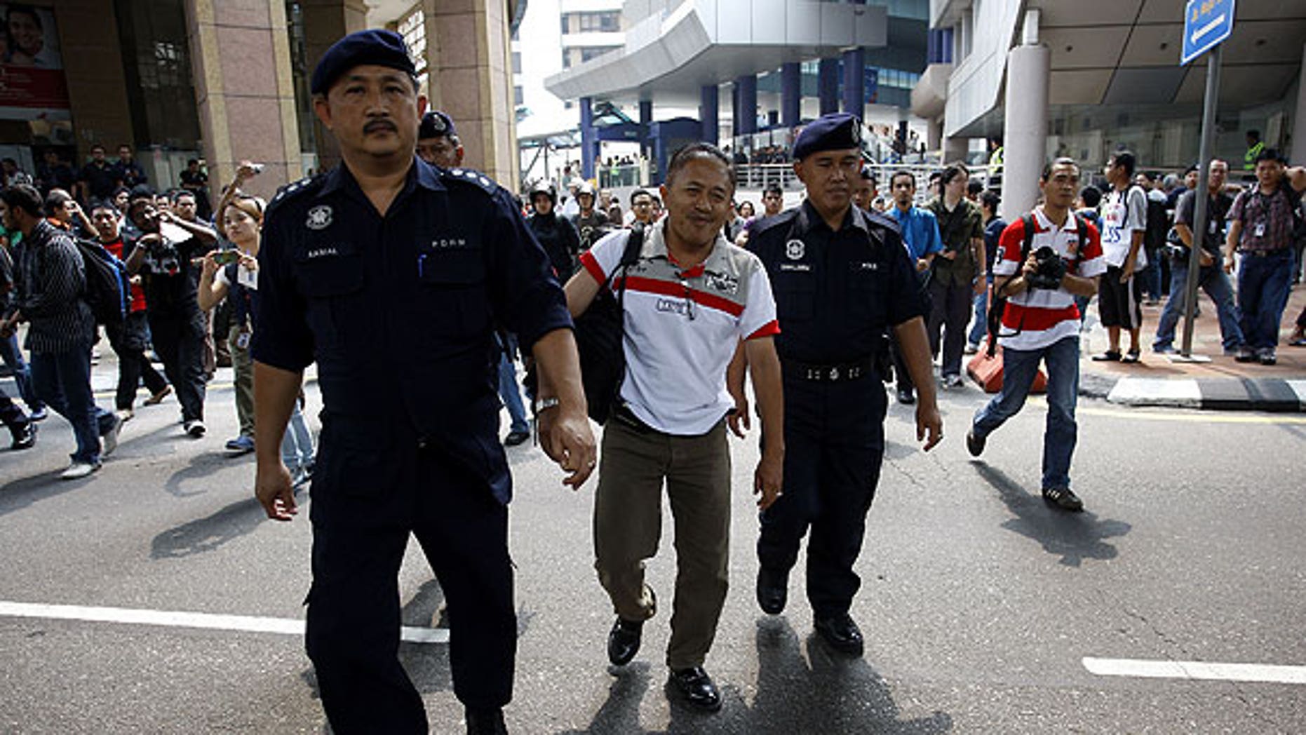 July 9: Malaysian police officers detain a man near Independence Square in Kuala Lumpur, Malaysia. Malaysian police said they have detained at least 644 people trying to assemble at a stadium for a banned rally seeking electoral reforms.