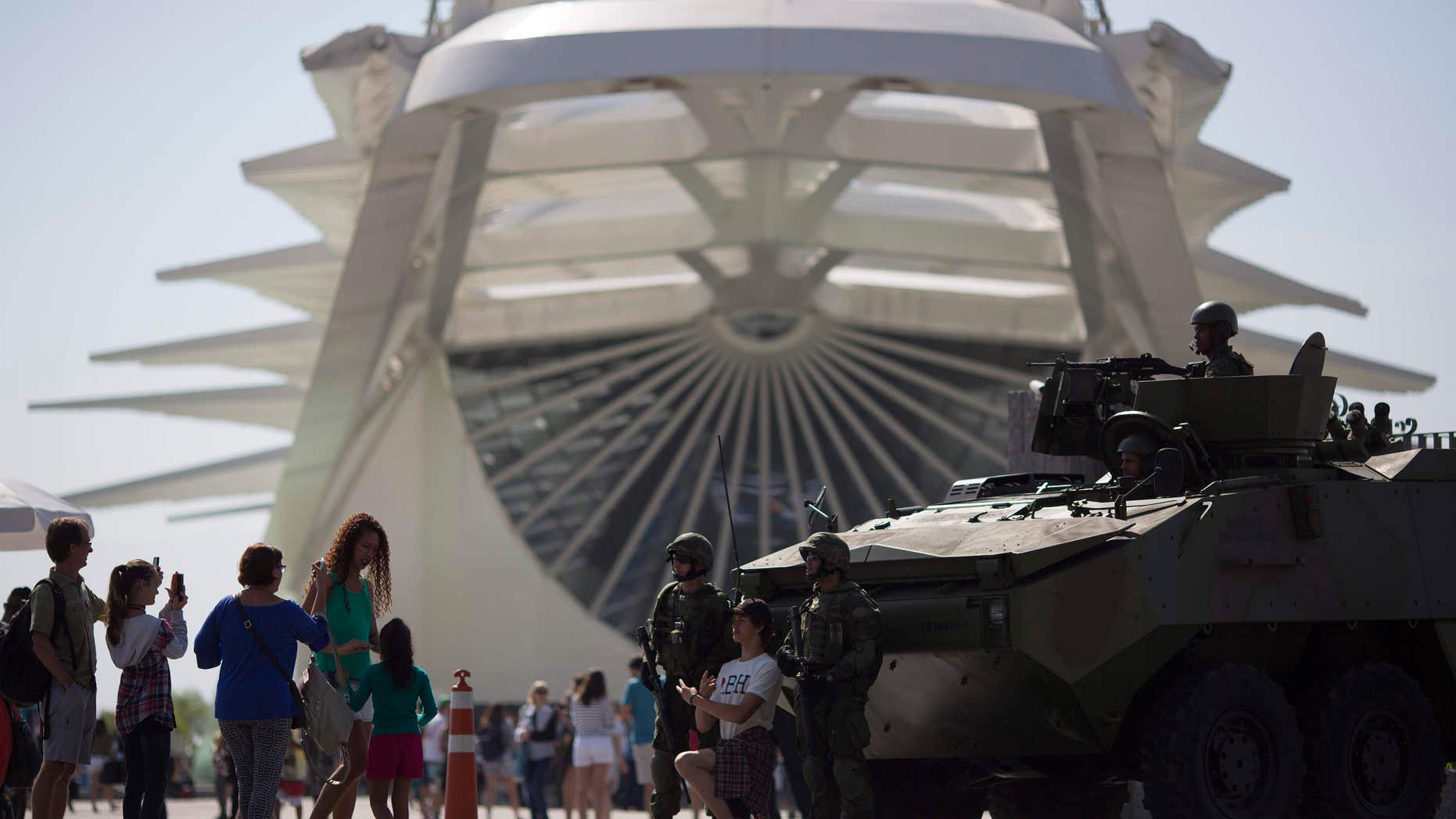 People take pictures with marines and their armored vehicle outside the Museum of Tomorrow in Rio de Janeiro, Brazil.