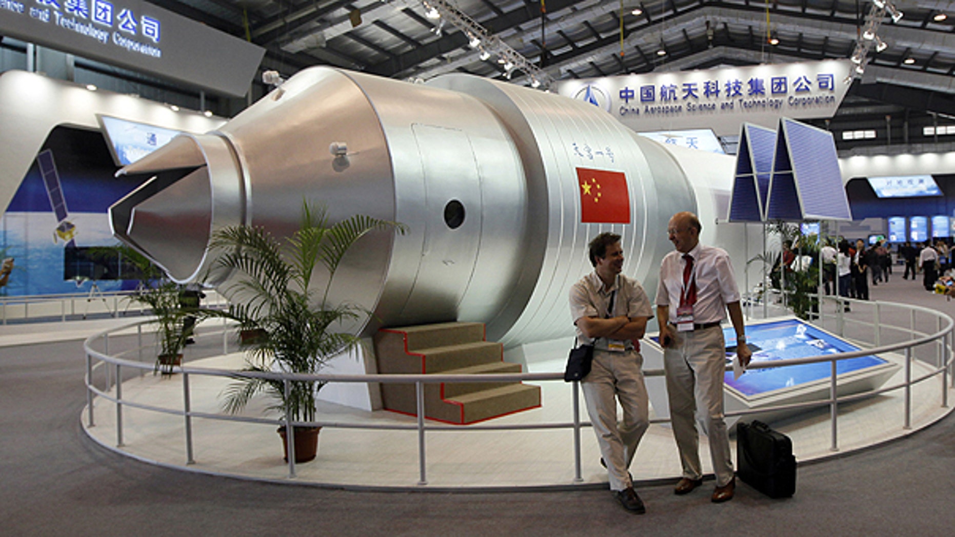 In this photo taken Nov. 16, 2010, visitors sit besides a model of Chinese made Tiangong 1 space station at the 8th China International Aviation and Aerospace Exhibition, known as Airshow China 2010, in Zhuhai city, south China, Guangdong province.