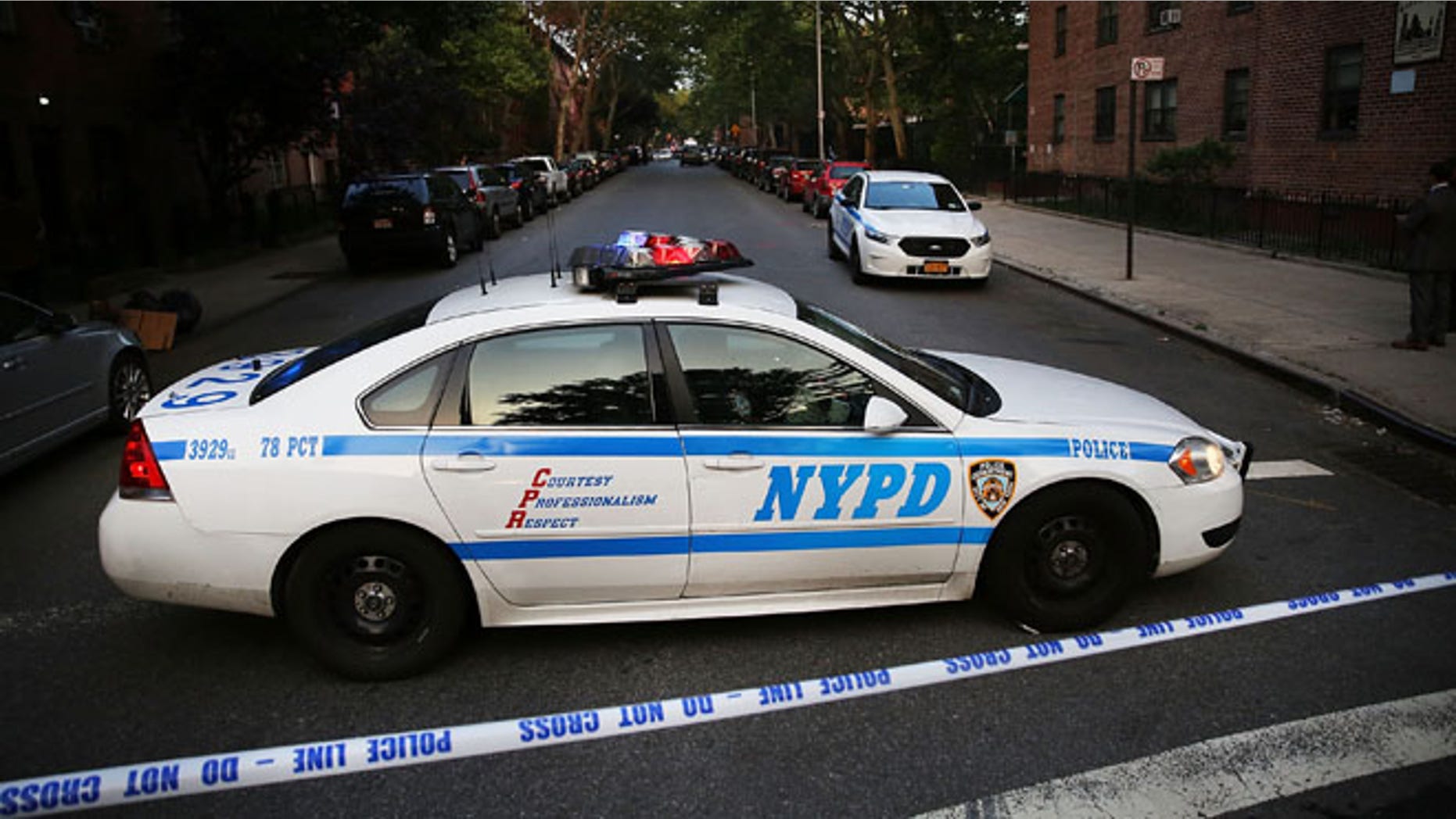 A police car is parked at a crime scene where three people were shot on June 10, 2015 in Brooklyn, N.Y.