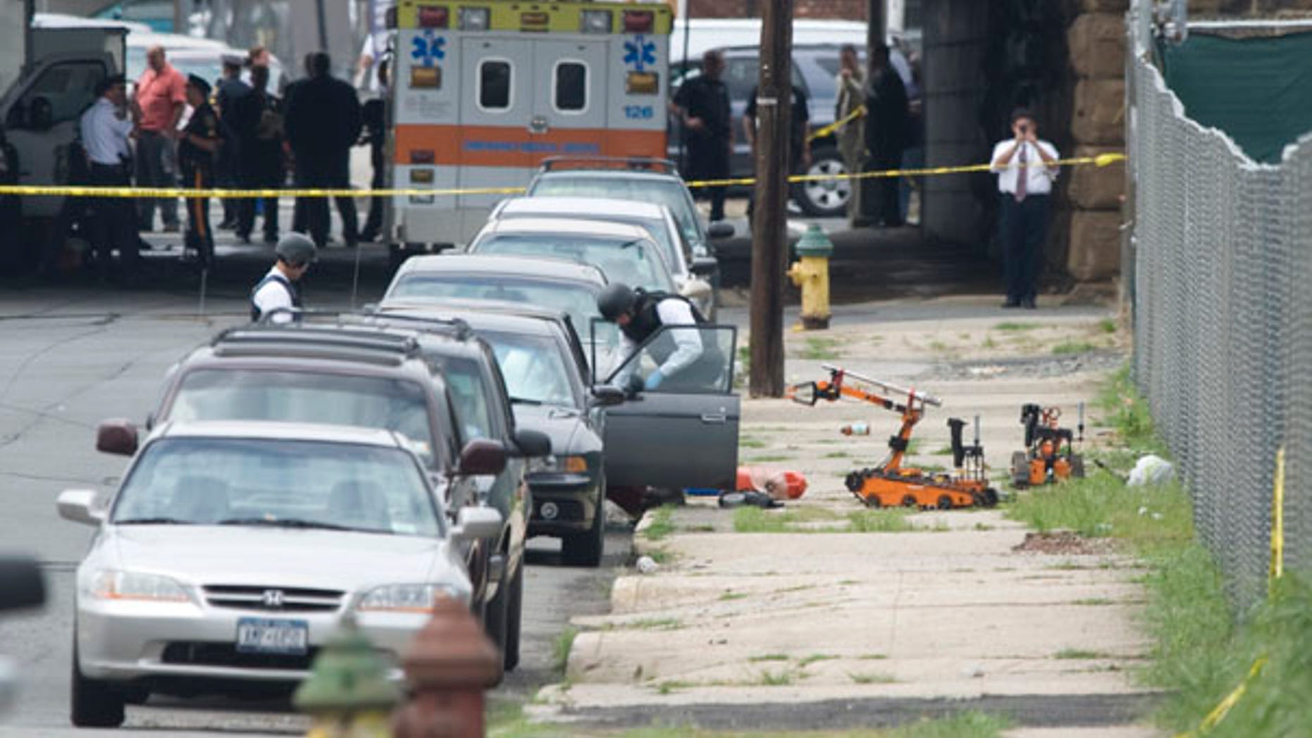 July 14: Police in protective gear look inside a car after they used robots to remove suspicious items from a car parked below a railroad overpass in Newark, N.J.