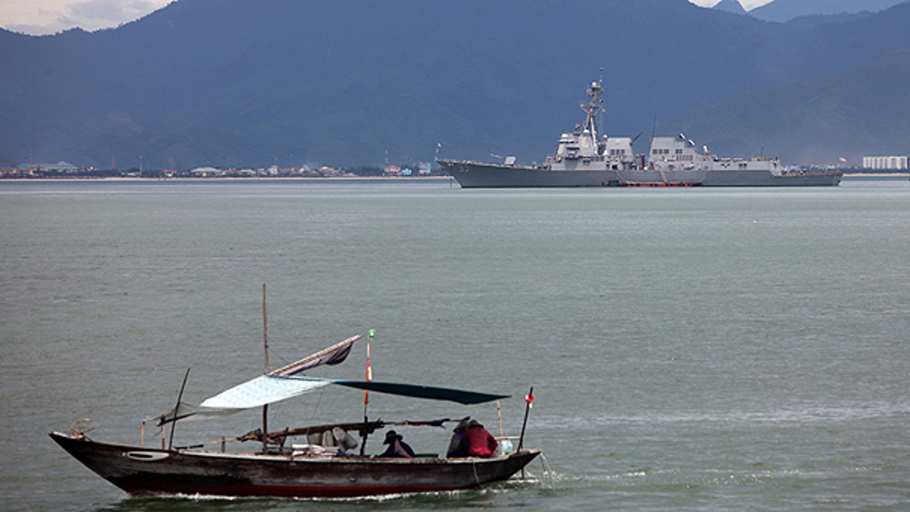 July 15: A Vietnamese fisher boat passes near the guided missile destroyer USS Chung-Hoon which is anchored on the background during a port visit for the naval exchange activities of the guided missile destroyers USS Chung-Hoon and USS Preble, as well as the rescue and salvage ship USNS Safeguard to Danang port, Danang province, Vietnam.