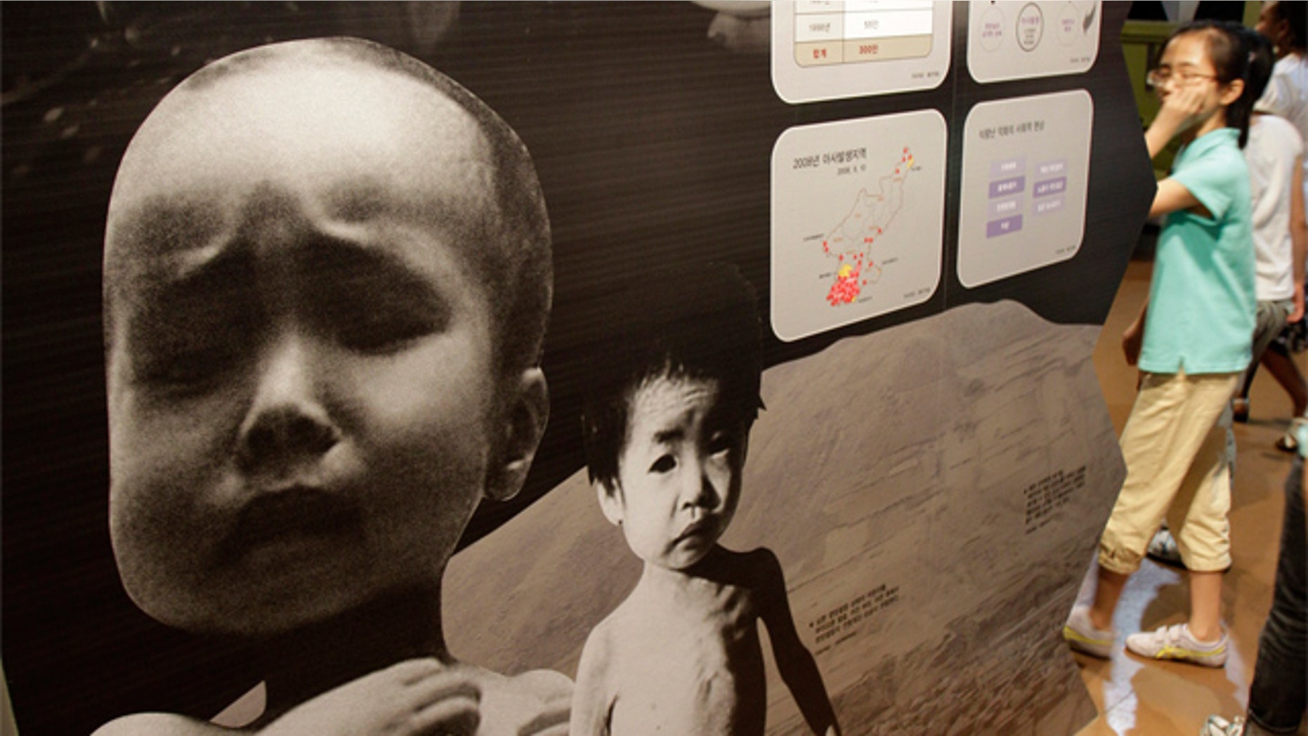 July 15: South Korean students walk by a picture showing a North Korean child suffering from famine at Korean War exhibition in Seoul, South Korea.
