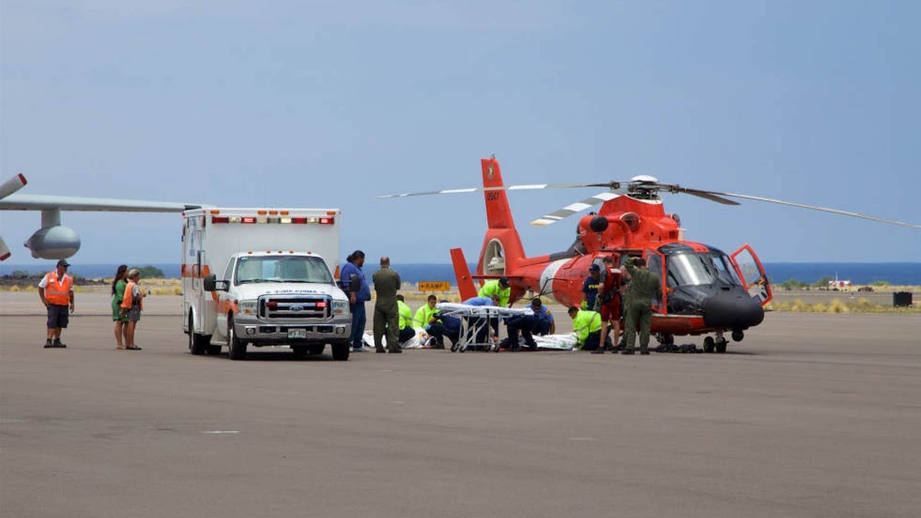 In this photo provided by the U.S. Coast Guard, Coast Guard crews safely deliver David McMahon and Sidney Uemoto to emergency medical personnel in Kona, Hawaii, Friday, July 15, 2016, following their rescue nine miles off Kona.