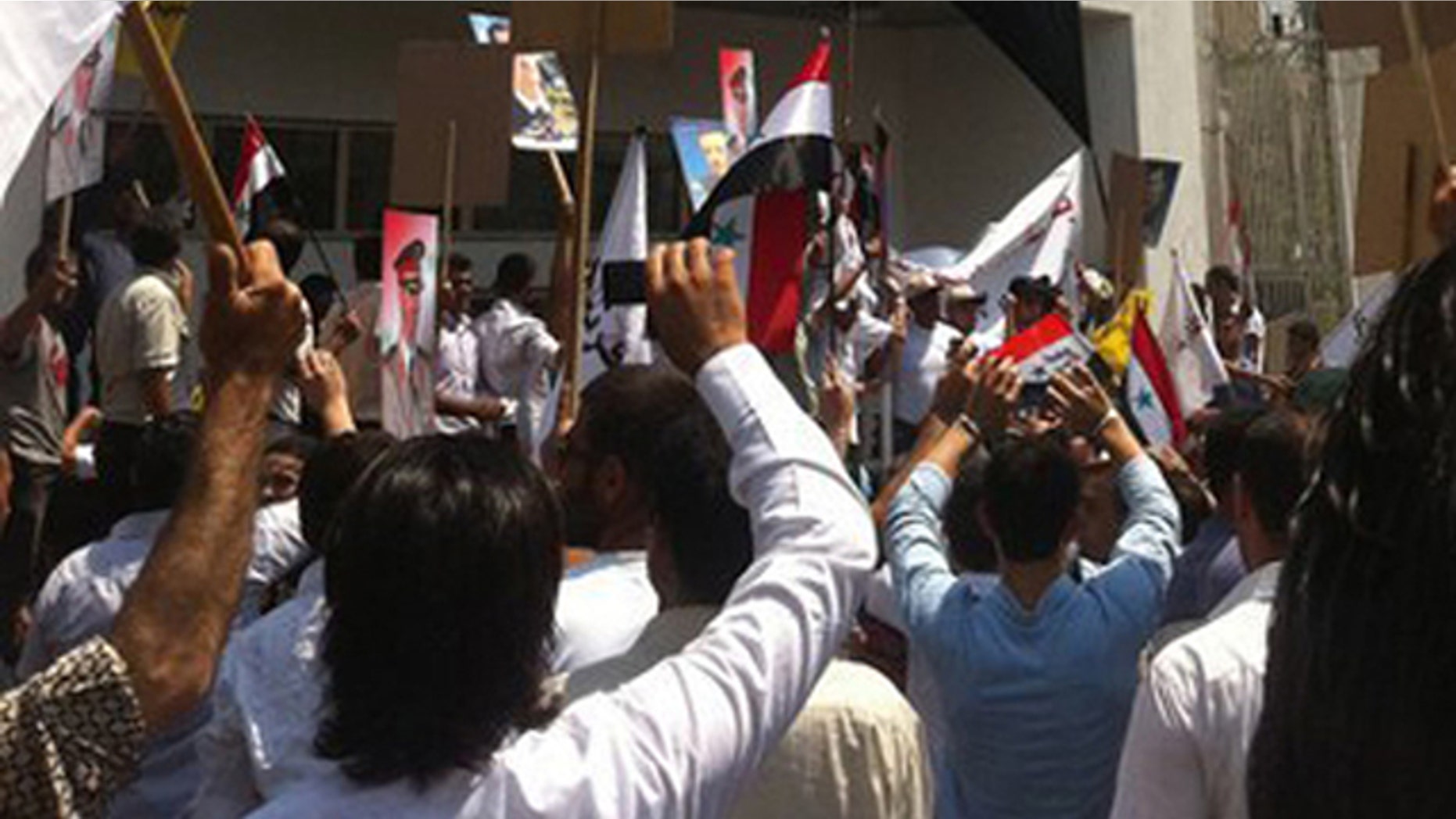 In this photo released by a Syrian news website Shukumaku, pro-Syrian President Bashar Assad protesters hang a huge Syrian flag at the entrance of the U.S. the embassy compound as they protest against the U.S. Ambassador Robert Ford after his visit to the Syrian city of Hama.