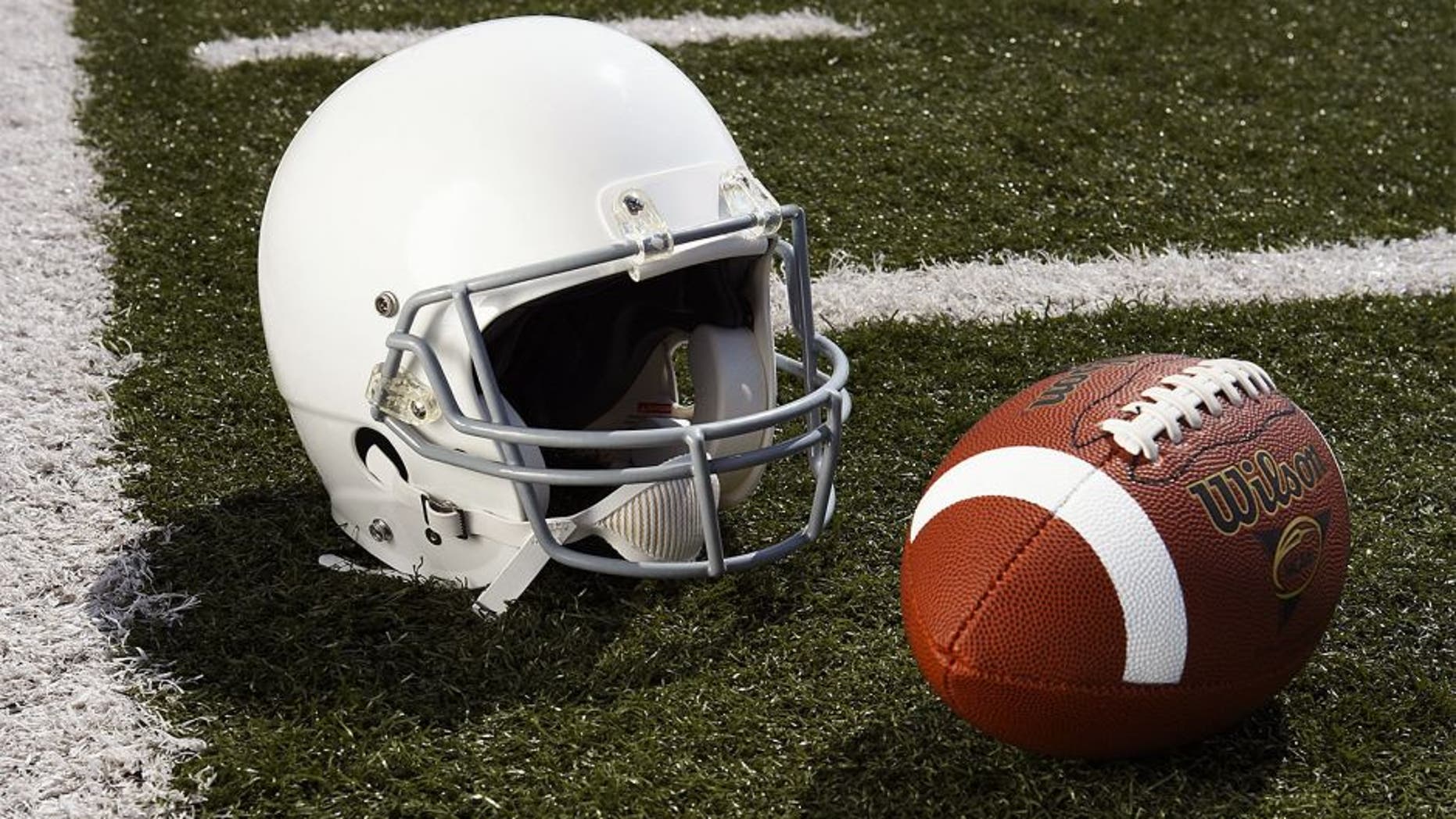 Football and football helmet on football field