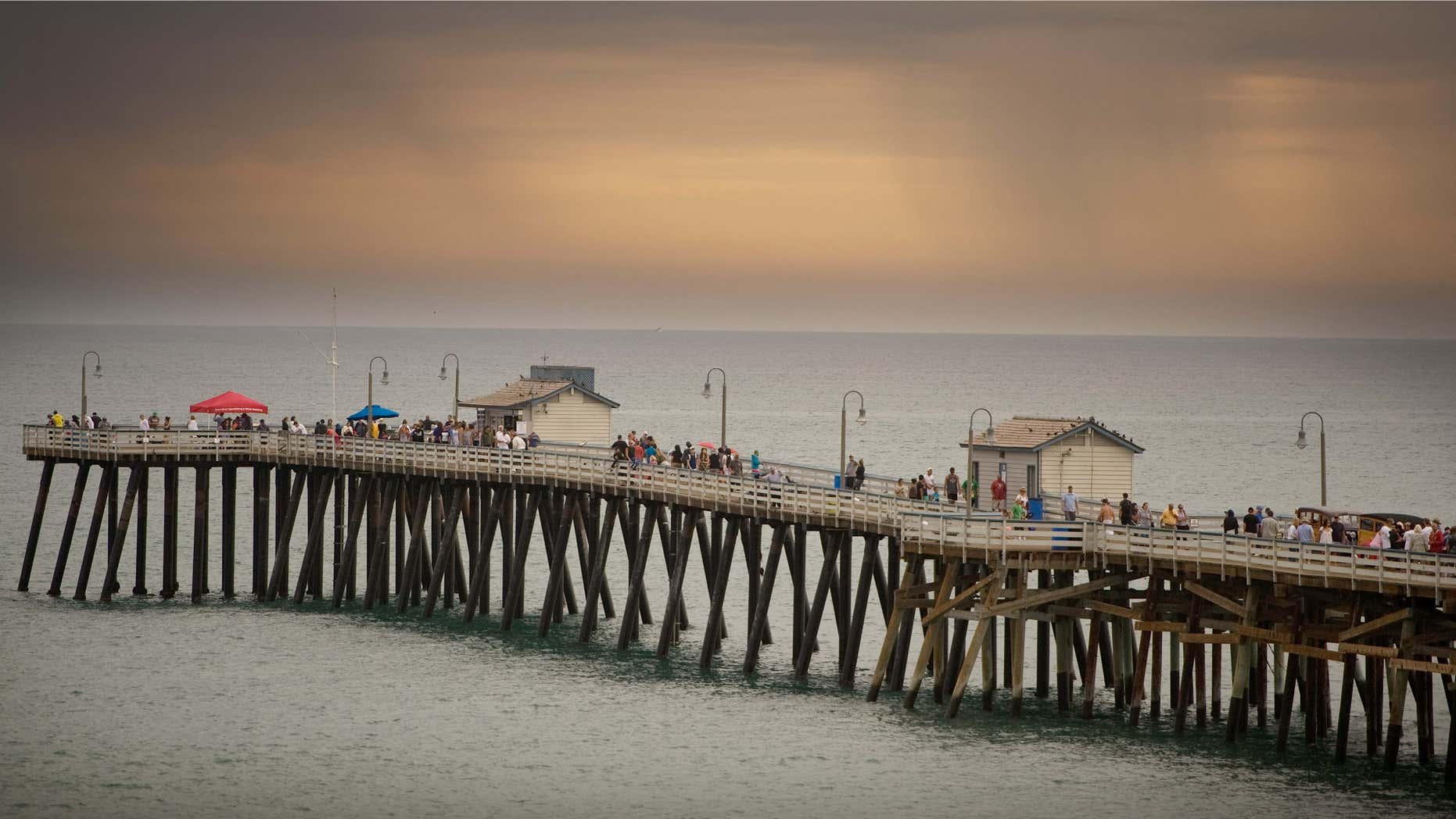 As storm clouds loom in the distance, lifeguards advise people to leave the pier and beach during the Ocean Festival in San Clemente, Calif.