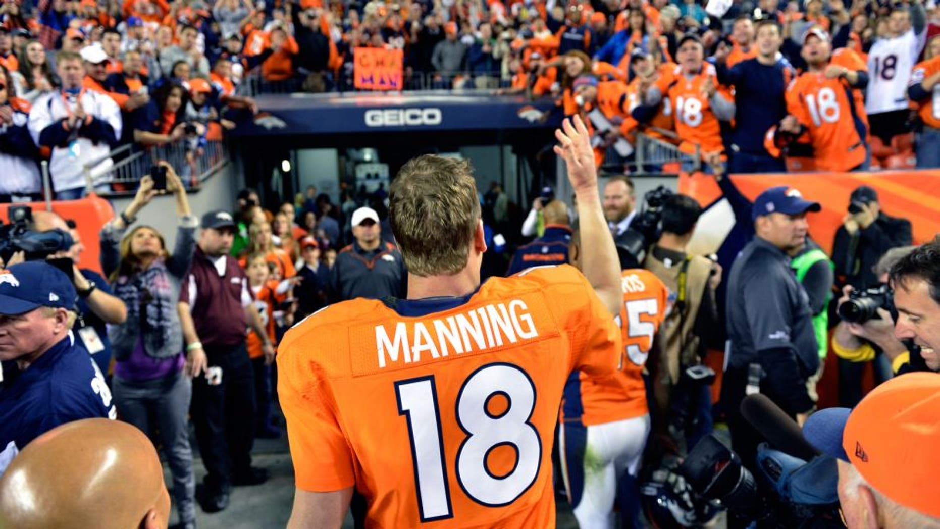 Dec 2 2012; Denver, CO, USA; Denver Broncos quarterback Peyton Manning (18) tosses a piece of equipment to the fans following the win over the Tampa Bay Buccaneers at Sports Authority Field. The Broncos defeated the Buccaneers 31-23. Mandatory Credit: Ron Chenoy-USA TODAY Sports
