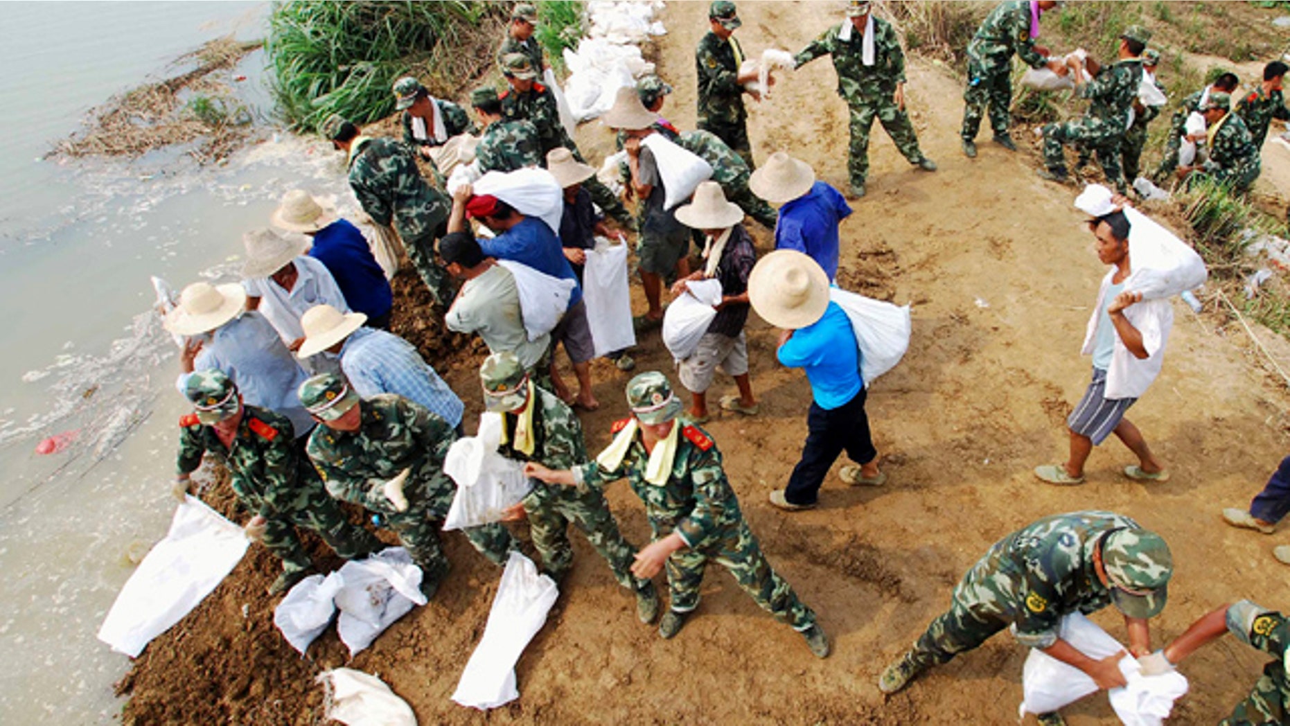 In this Tuesday, July 20, 2010 photo, paramilitary police and workers move sandbags to fortify the Fanghu dyke in Pengze county, in central China's Jiangxi province. Flooding this year has killed 701 people, left 347 missing and caused tens of billions of dollars in damage, the worst toll across the board that China has seen in a decade, a senior Chinese official said Wednesday. (AP Photo) ** CHINA OUT **
