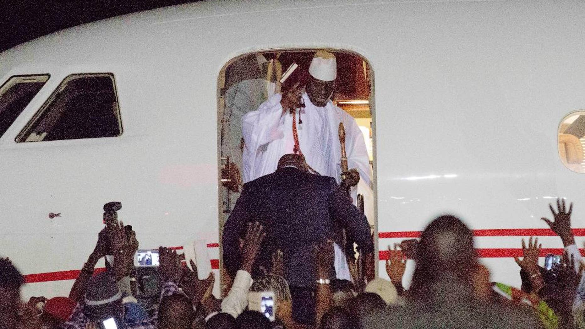 FILE - In this file photo dated Saturday Jan. 21, 2017, Gambia's defeated leader Yahya Jammeh, top wearing white, waves to supporters as he goes into exile from Gambia's capital Banjul airport. Jammeh fiercely denounced homosexuality and warned gay people to leave the country with threats to "cut of the head" of any who remained, so Jammeh's departure "is a great relief for the population, and especially the LGBT population who were often martyred under his rule," said Lambert Lamba, a leading gay rights activist in Cameroon. (AP Photo/Jerome Delay, FILE)