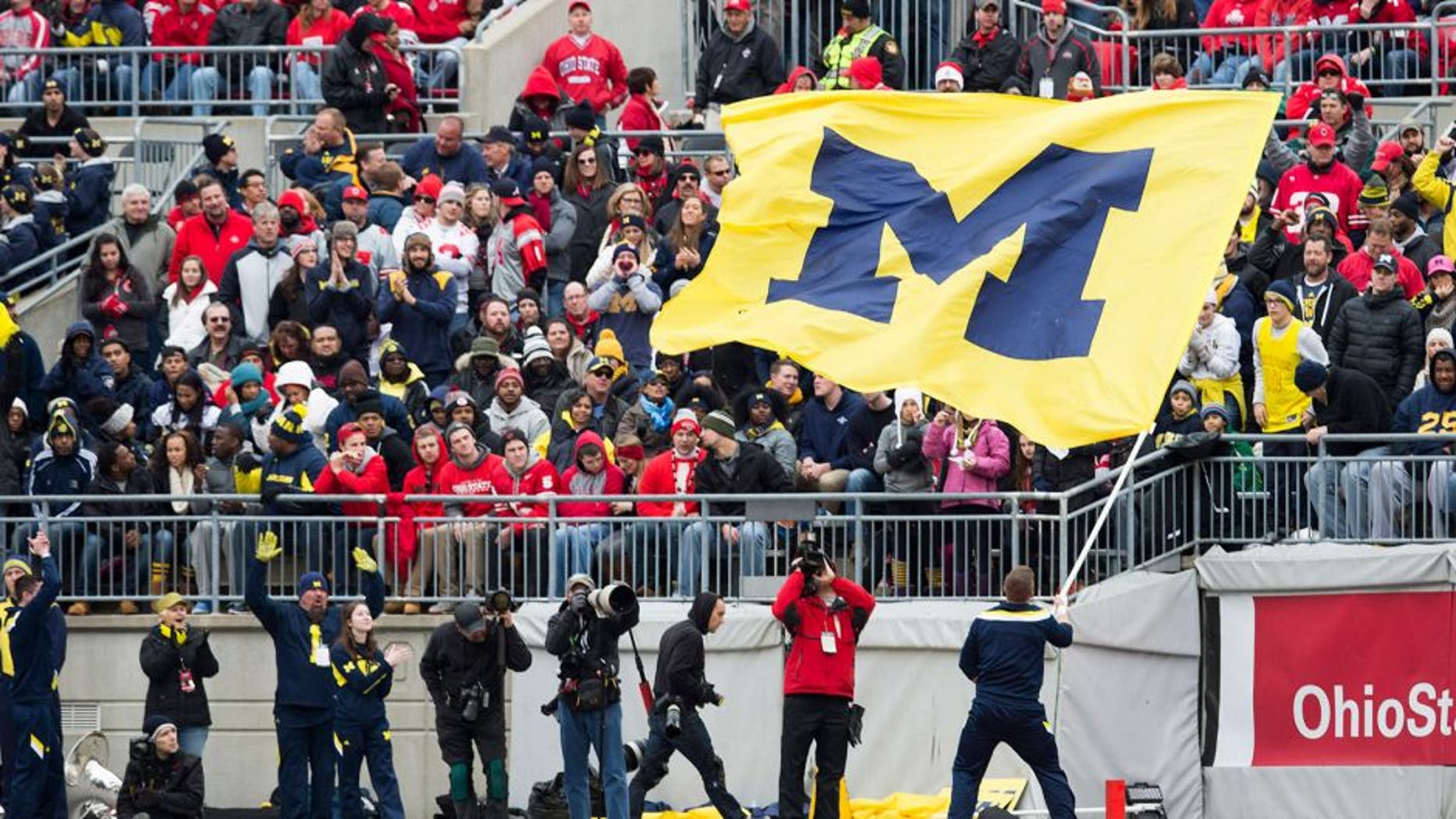 Nov 29, 2014; Columbus, OH, USA; A Michigan Wolverines cheerleader waves the Michigan flag in front of Ohio State Buckeyes fans at Ohio Stadium. Ohio State won the game 42-28. Mandatory Credit: Greg Bartram-USA TODAY Sports
