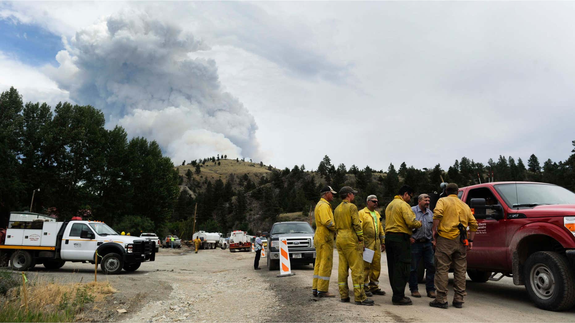 July 21, 2015: Wildland firefighters chat with Deep Creek landowners as smoke rises from a wildfire near Townsend, Mont.