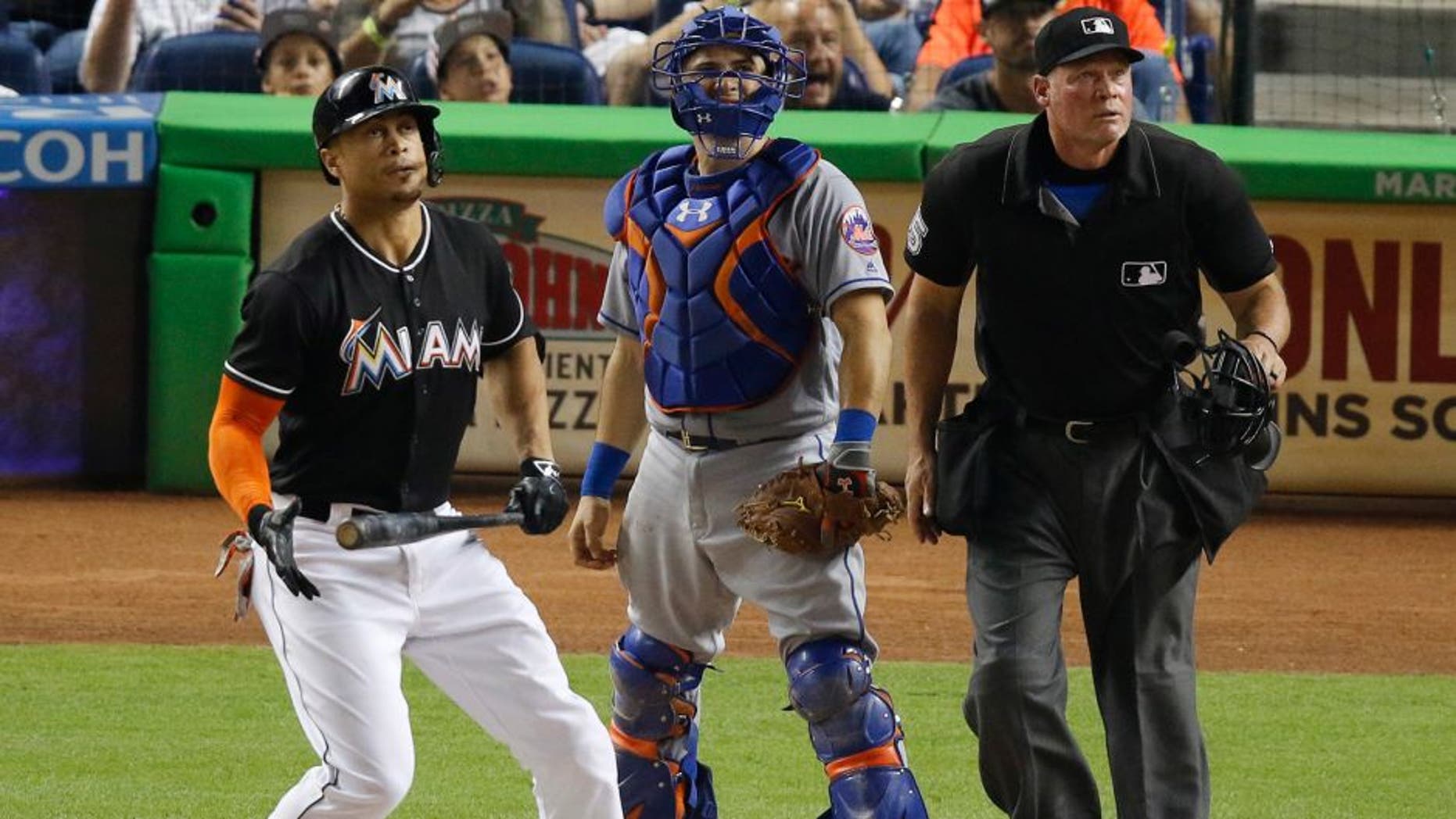 Miami Marlins' Giancarlo Stanton, left, watches his two-run home run in the third inning in front of New York Mets catcher Travis d'Arnaud during a baseball game in Miami, Saturday, July 23, 2016. (AP Photo/Joe Skipper)