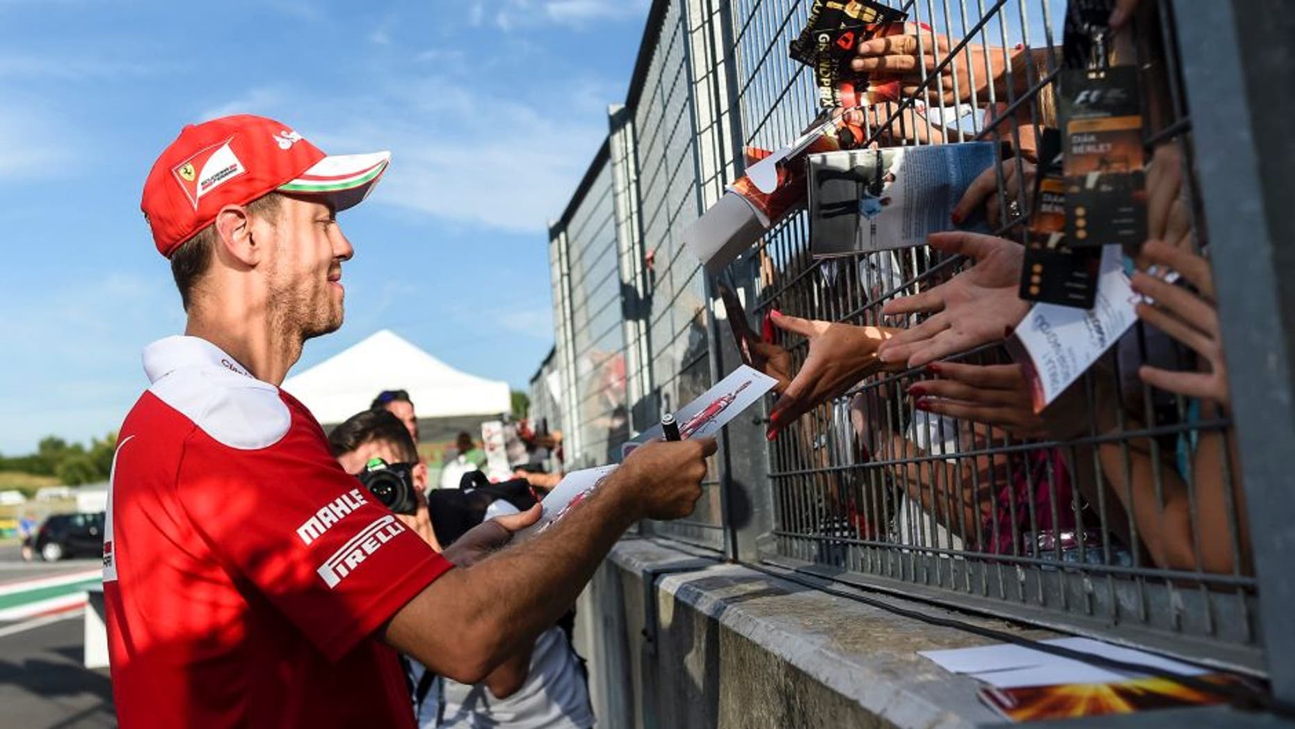 Ferrari driver Sebastian Vettel of Germany signs autographs at the Hungaroring racetrack, in Budapest, Hungary, Thursday, July 21, 2016. The Hungarian Formula One Grand Prix will be held on Sunday July, 24. (Janos Marjai/MTI via AP)