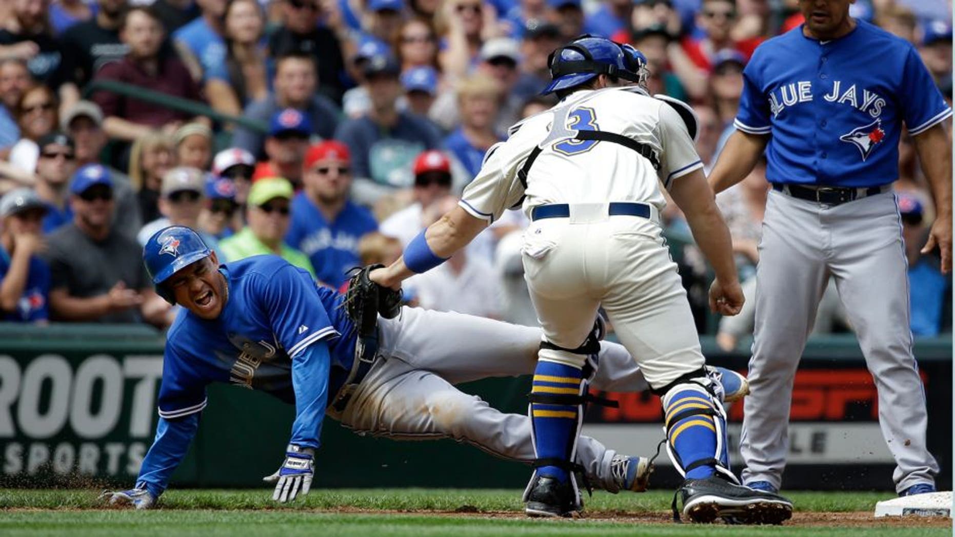 Seattle Mariners catcher Mike Zunino, center, tags Toronto Blue Jays' Ezequiel Carrera, left, out at third base as third base coach Luis Rivera looks on at the end of a triple play in the fourth inning of a baseball game Sunday, July 26, 2015, in Seattle. (AP Photo/Elaine Thompson)