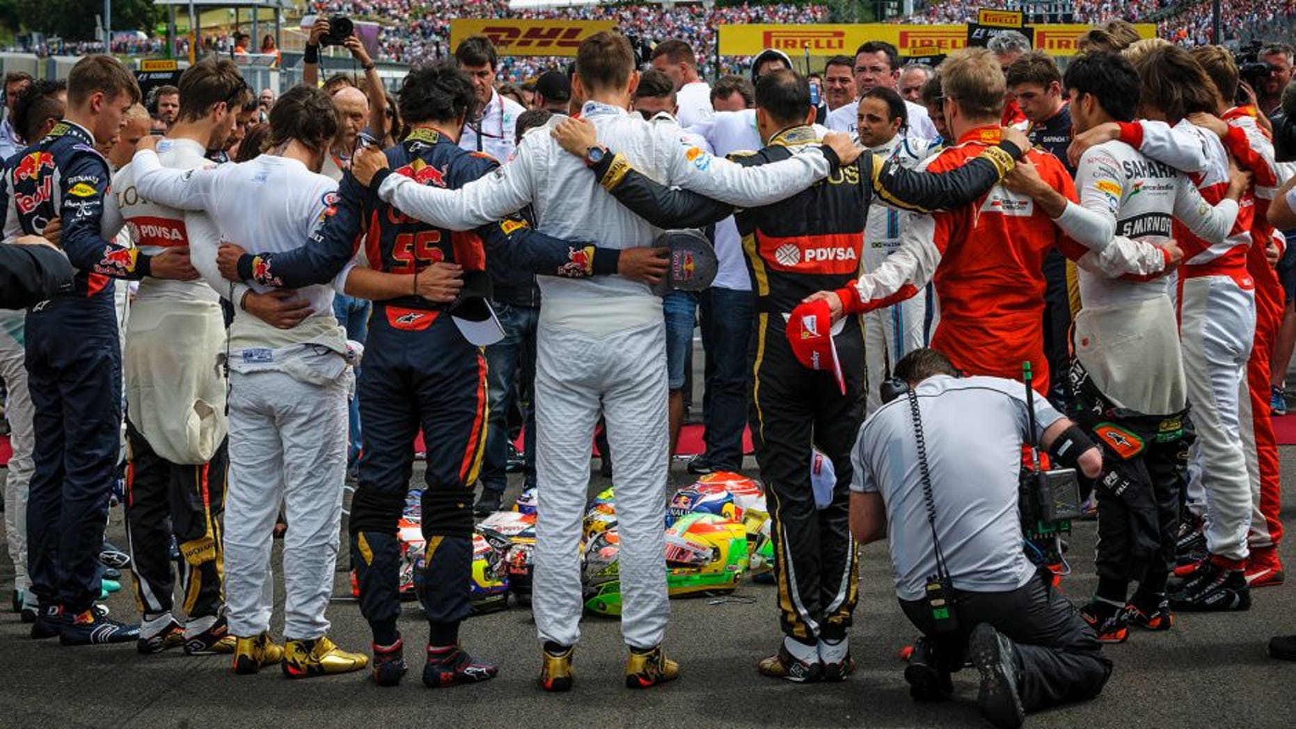 Forming a circle Formula One drivers embrace for a minute of silence to pay tribute to their recently deceased French colleague Jules Bianchi before the Formula One Hungarian Grand Prix on the Hungaroring circuit in Mogyorod, 23 km north east of Budapest, Hungary, Sunday, July 26, 2015. (Zsolt Czegledi/MTI via AP)