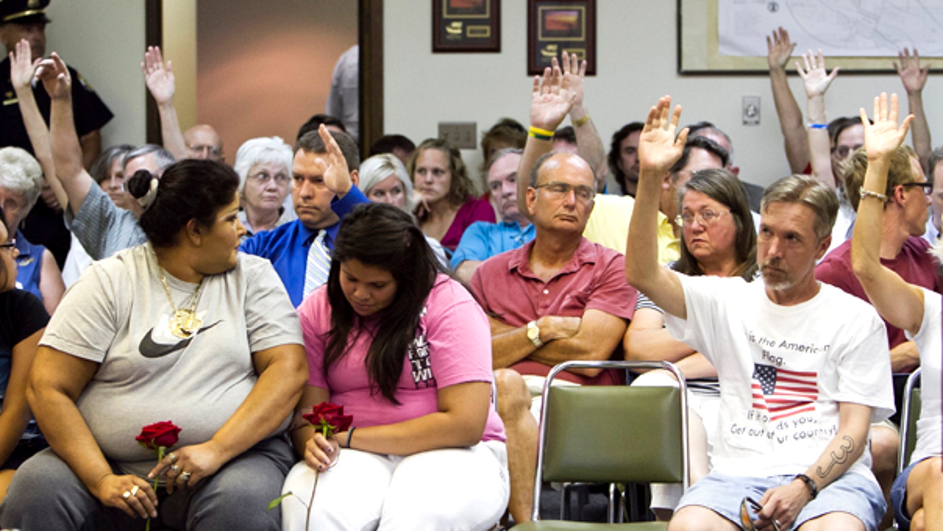 July 27: Two women in the front react to a show of hands of Fremont citizens who agree with a speaker who was in favor of implementing a city ordinance against illegal immigrants, in Fremont, Neb. (AP)
