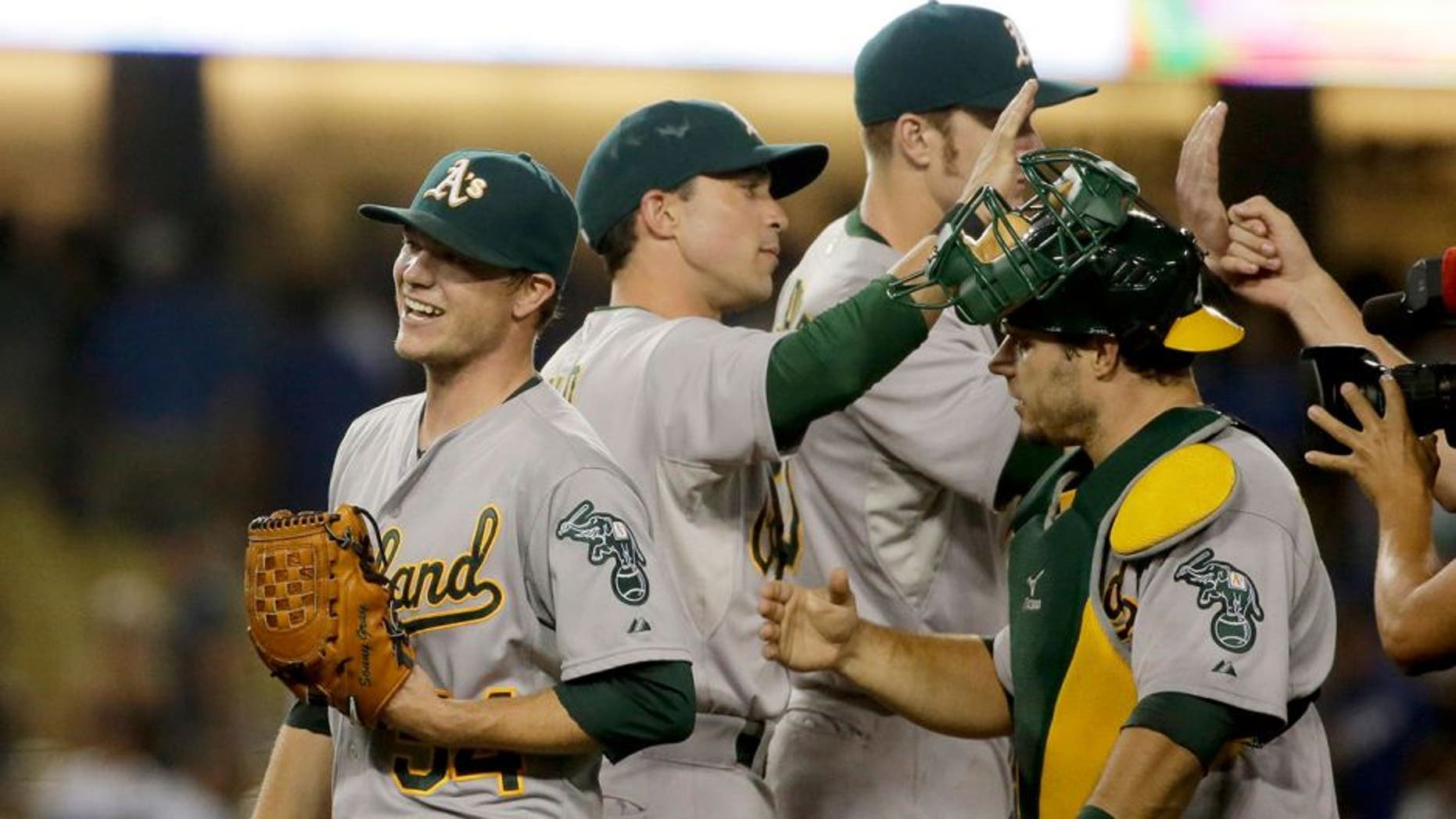 Oakland Athletics starting pitcher Sonny Gray, left, celebrates with teammates after they shutout the Los Angeles Dodgers 2-0 in a baseball game, Tuesday, July 28, 2015, in Los Angeles. (AP Photo/Chris Carlson)