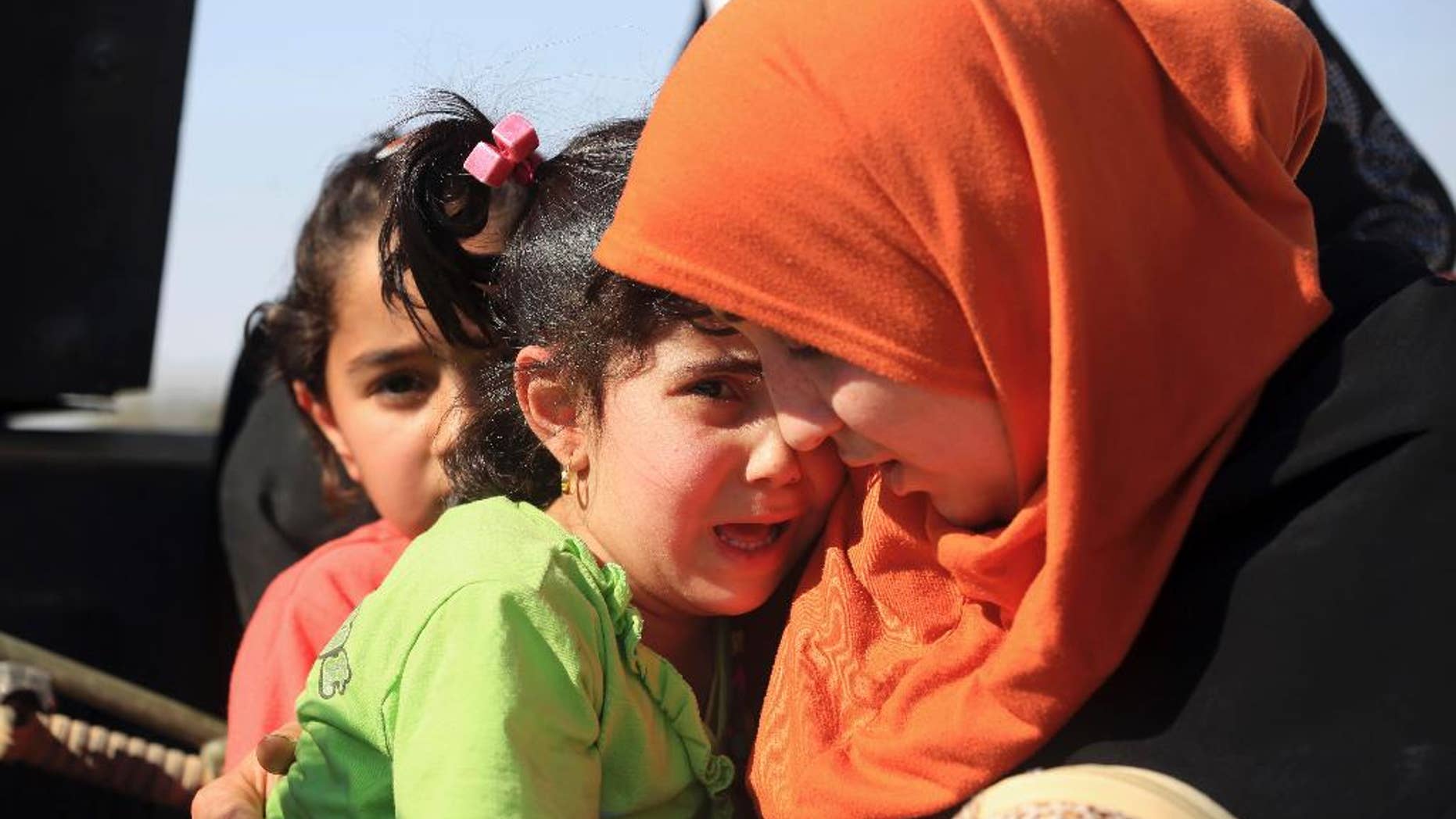 FILE - In this Monday, April 4, 2016 file photo, people flee their homes during clashes between Iraqi security forces and Islamic State group in Hit, 85 miles (140 kilometers) west of Baghdad, Iraq. Families, many with small children and elderly relatives say they walked for hours Monday through desert littered with roadside bombs to escape airstrikes and clashes. (AP Photo/Khalid Mohammed, File)