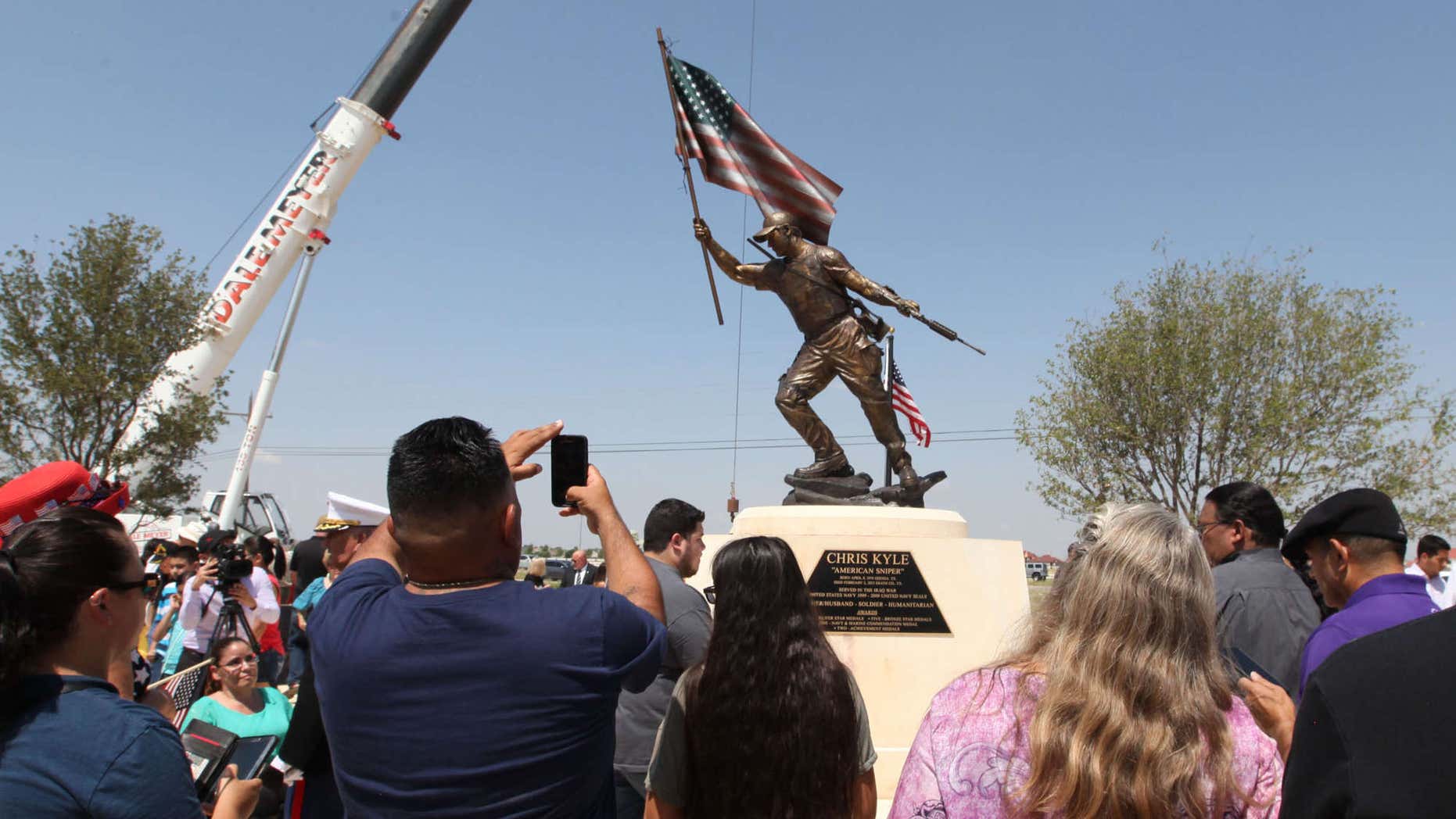 Supporters and spectators take photos of the Chris Kyle statue after the unveiling Thursday, July 28, 2016 at the Chris Kyle Memorial Plaza in Odessa, Texas.