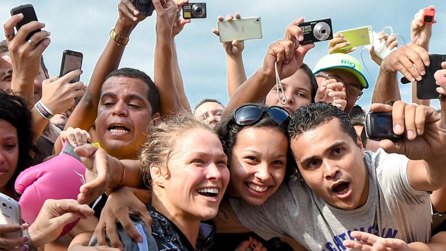 RIO DE JANEIRO, BRAZIL - JULY 29: Womens bantamweight champion Ronda Rousey of the United States takes photos with fans during open training session at Pepe Beach on July 29, 2015 in Rio de Janeiro, Brazil. (Photo by Buda Mendes/Zuffa LLC/Zuffa LLC via Getty Images)