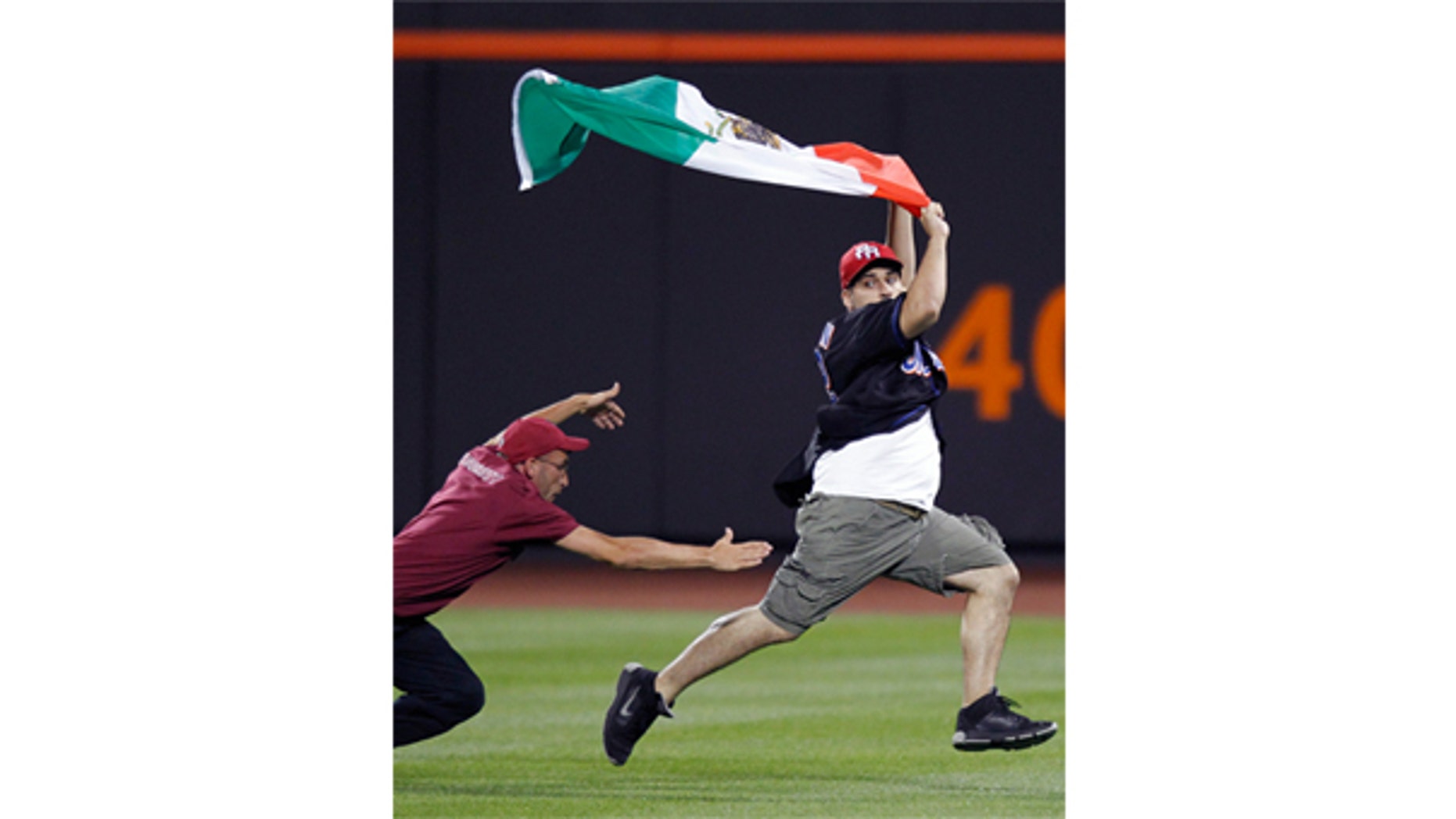 July 30: A Citi Field security guard tries to tackle a young man carrying a Mexican flag who ran onto the field in the seventh inning of the New York Mets vs the Arizona Diamondbacks baseball game in New York.