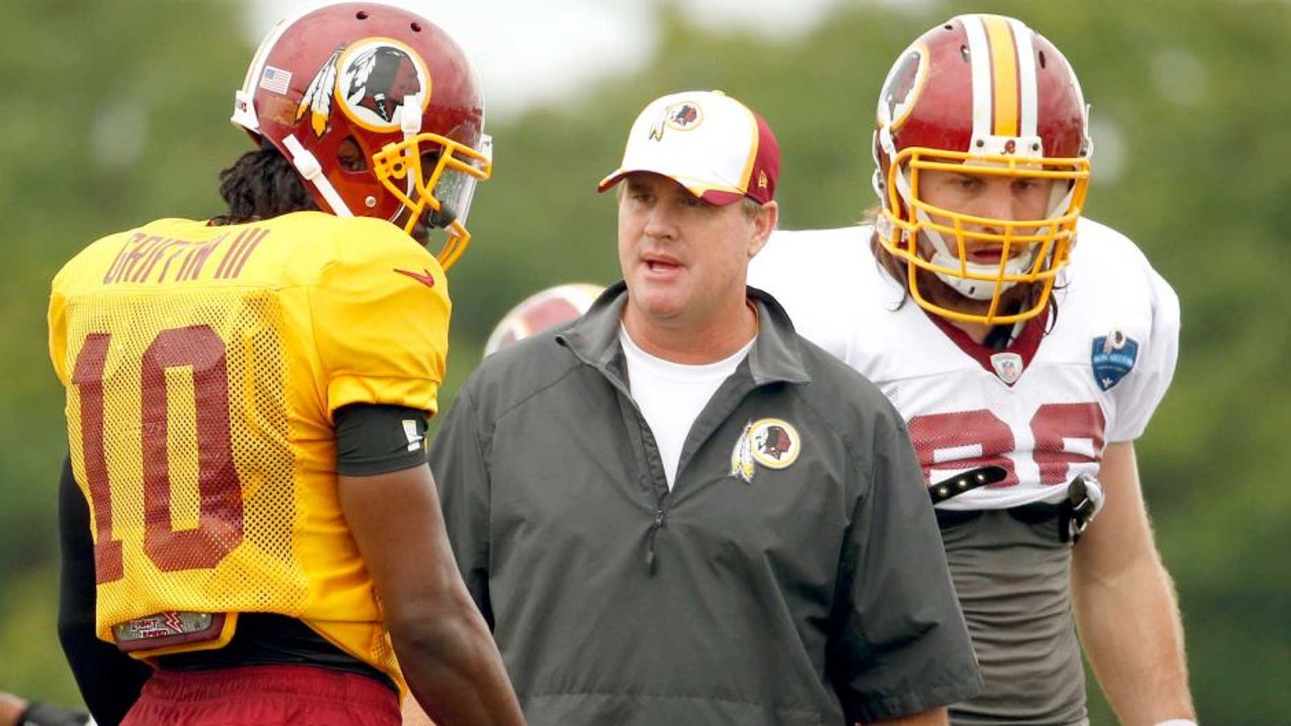 Washington Redskins head coach Jay Gruden, center, talks with quarterback Robert Griffin III, with tight end Logan Paulsen, right, during practice at the team's NFL football training facility, Sunday, July 27, 2014 in Richmond, Va. (AP Photo/Alex Brandon)