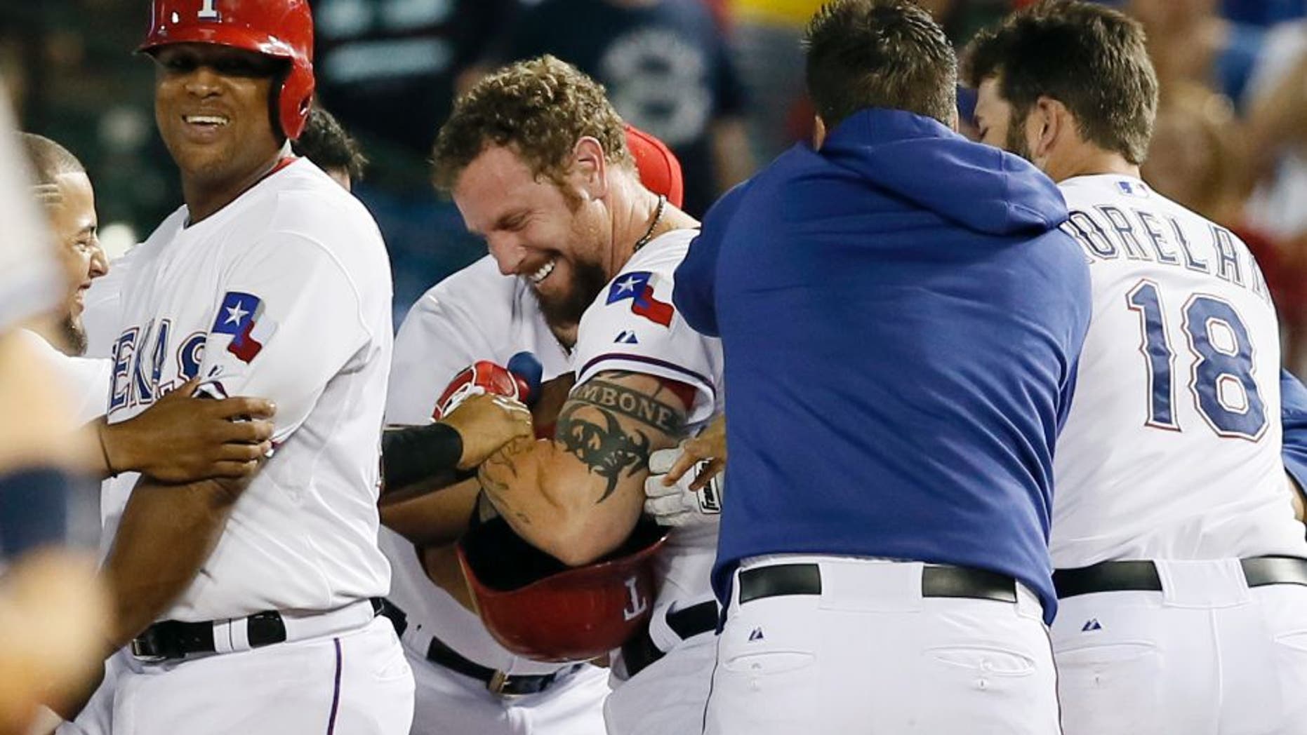 Texas Rangers' Adrian Beltre, left, Mitch Moreland (18) and others celebrate with Josh Hamilton, second from left, after Hamilton hit a walk off single against the Texas Rangers in the ninth inning of a baseball game Thursday, July 30, 2015, in Arlington, Texas. The hit scored Leonys Martin in the 7-6 Rangers win. (AP Photo/Tony Gutierrez)