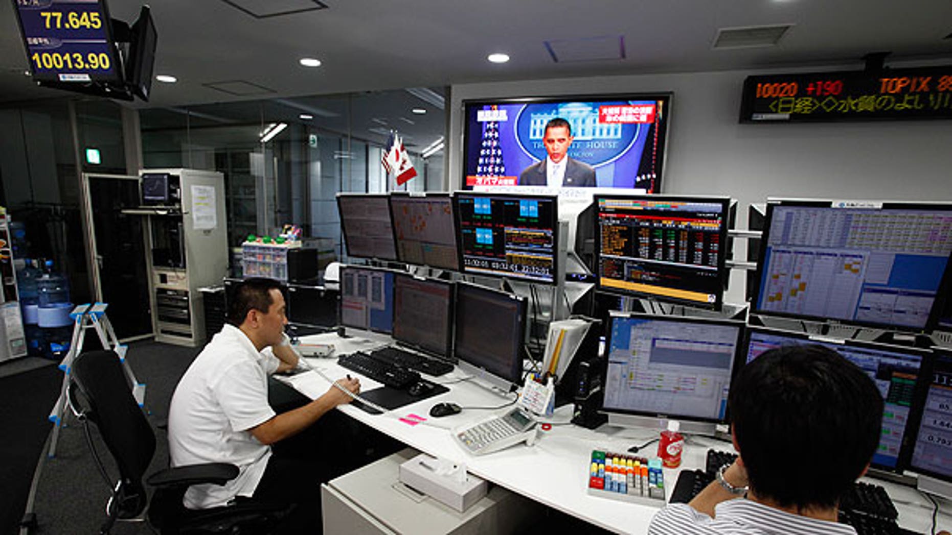 Aug. 1: Employees of a foreign exchange firm monitor screens, with a television news reports that President Obama announced U.S. debt limit deal, in Tokyo.