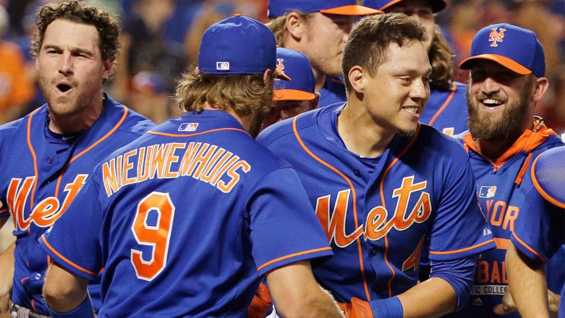 New York Mets' Wilmer Flores, center right, is mobbed by teammates after hitting a walkoff solo home run during the twelfth inning of a baseball game to defeat the Washington Nationals 2-1, Friday, July 31, 2015, in New York. (AP Photo/Julie Jacobson)