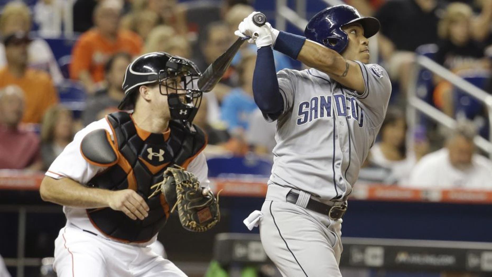 San Diego Padres' Alexi Amarista, right, follows through on a sacrifice fly to score Derek Norris in the fourth inning of a baseball game against the Miami Marlins, Friday, July 31, 2015, in Miami. At left is Miami Marlins catcher J.T. Realmuto. (AP Photo/Lynne Sladky)